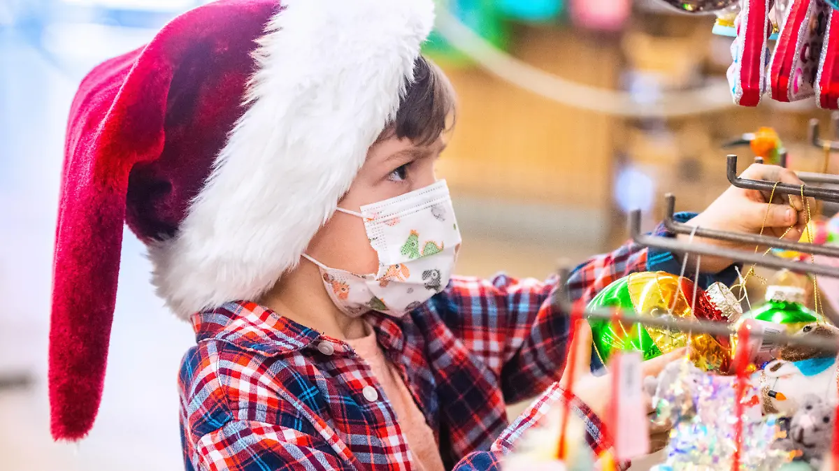 Pensive Caucasian Little boy shopping for Christmas decorations wearing a Santa hat