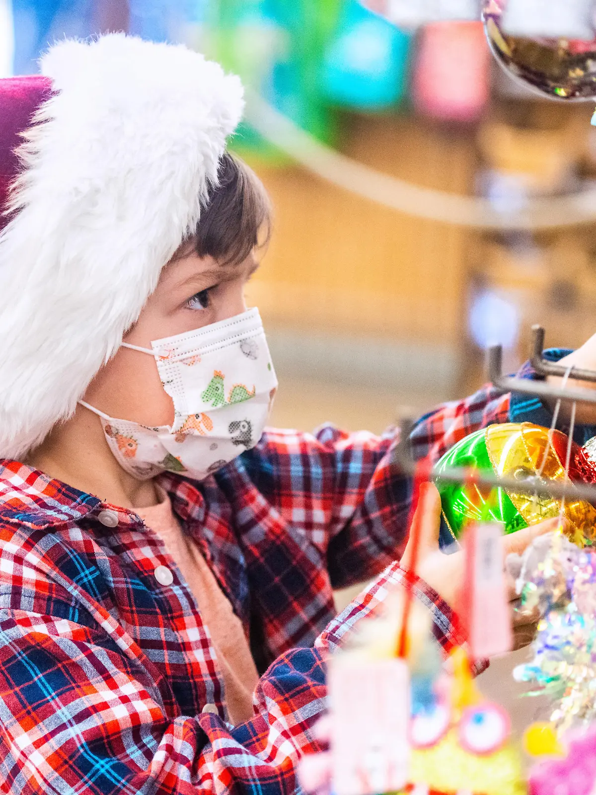 Pensive Caucasian Little boy shopping for Christmas decorations wearing a Santa hat
