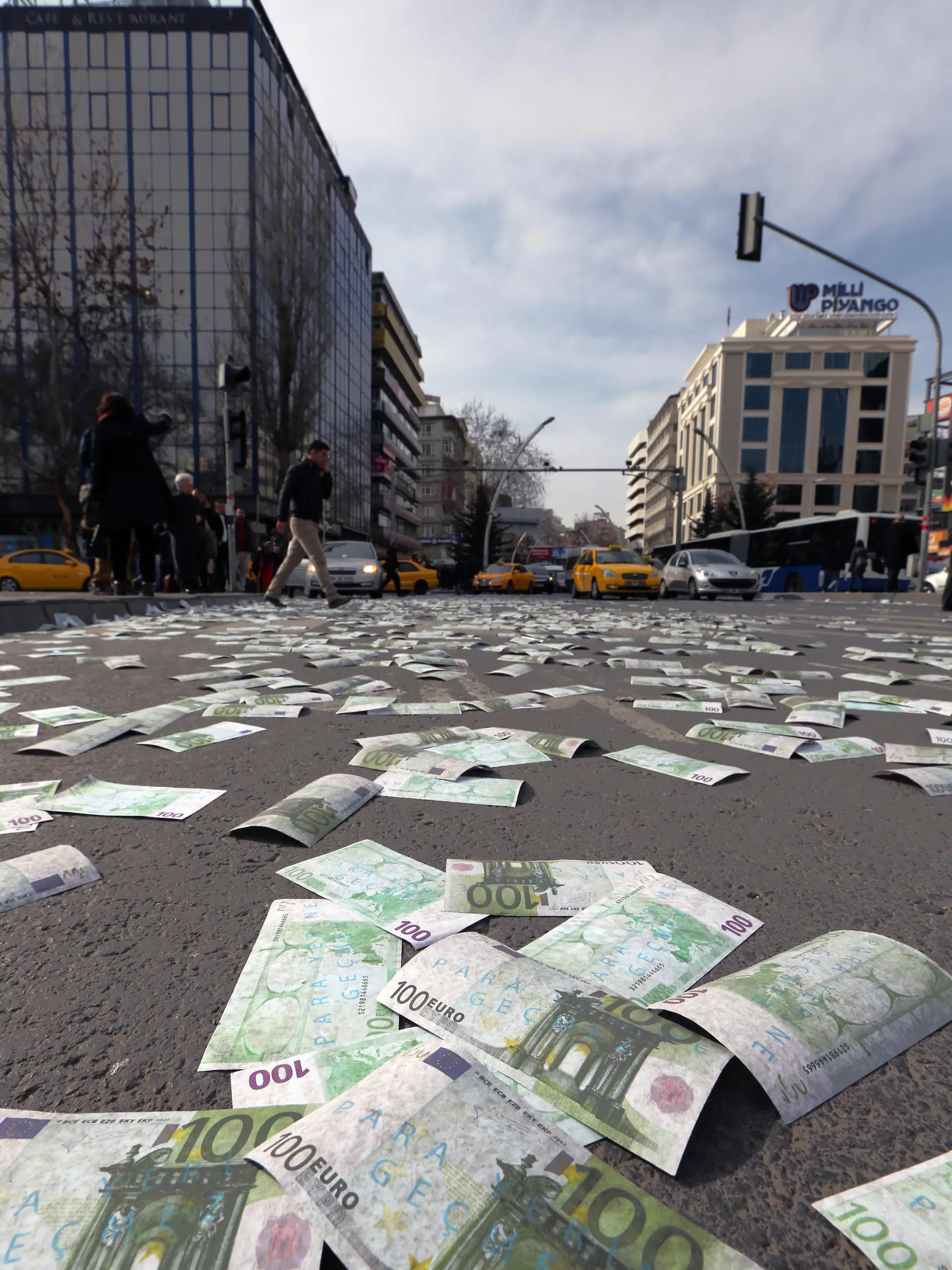 Cars wait for green light on a main road covered with banknotes after members of the main opposition Republican People's Pary, CHP, has thrown fake Euro bills into the air during an anti-government protest denouncing a corruption scandal that has shaken Prime Minister Recep Tayyip Erdogan¿s government, in Ankara, Turkey, Saturday, March 1, 2014. Protesters shouted ¿there¿s a thief! ¿ as they distributed an amount of 30 million fake bills, a day after five remaining suspects jailed in a vast corruption investigation that has shaken Erdogan¿s government, including two former ministers¿ sons and a businessman suspected of bribery and illicit money transfers to Iran, have been released on parole pending trial.(AP Photo/Burhan Ozbilici)