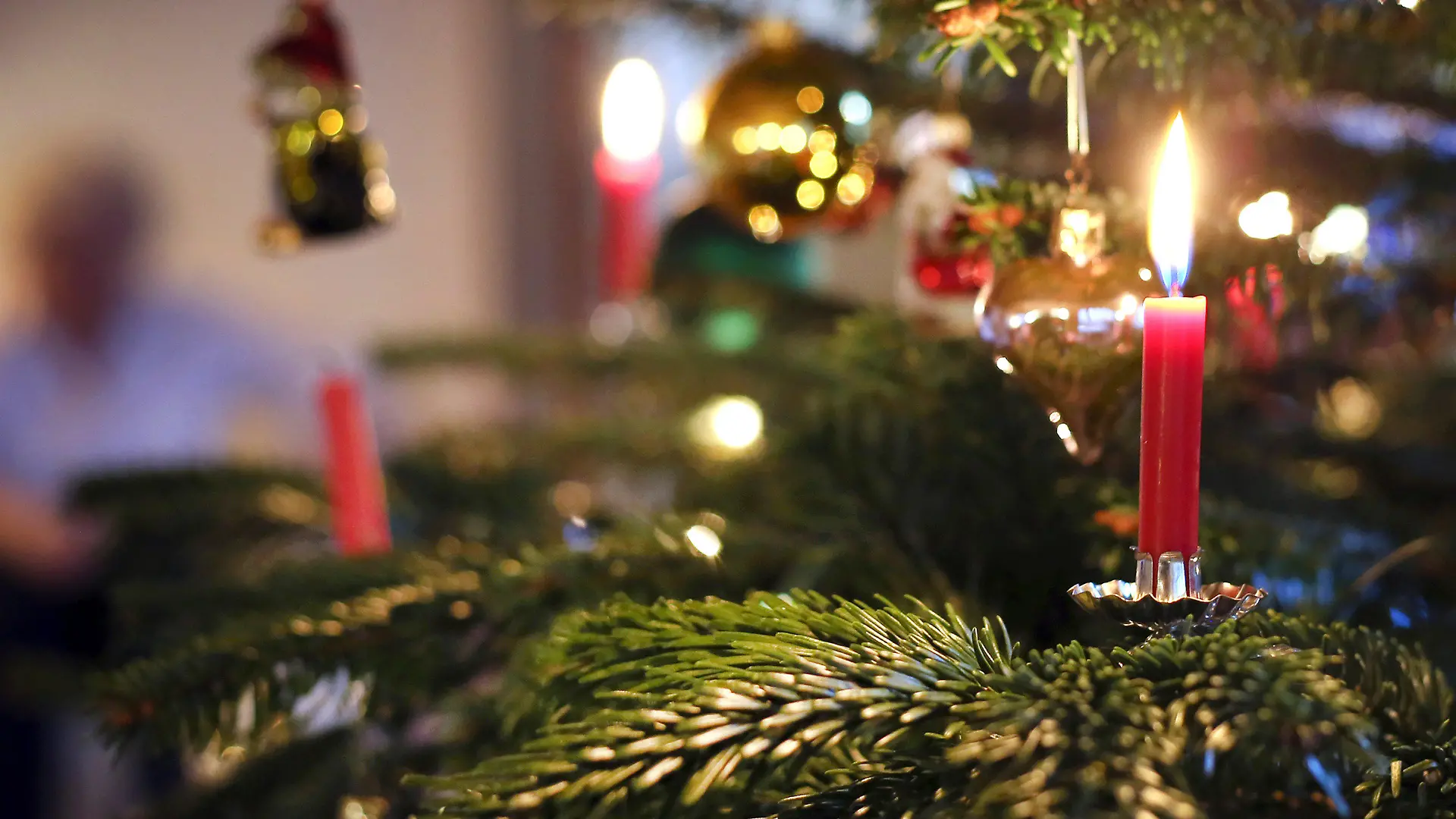 ARCHIV - 25.12.2019, Bayern, Kaufbeuren: Kerzen brennen an einem festlich geschmückten Weihnachtsbaum. Bundeskanzler Scholz (SPD) und die Ministerpräsidentinnen und -präsidenten der Länder beraten über erneute Maßnahmenverschärfungen, um der befürchteten Omikron-Welle in der Corona-Pandemie begegnen. Die Regeln für Weihnachten bleiben voraussichtlich wie sie sind. Foto: Karl-Josef Hildenbrand/dpa +++ dpa-Bildfunk +++