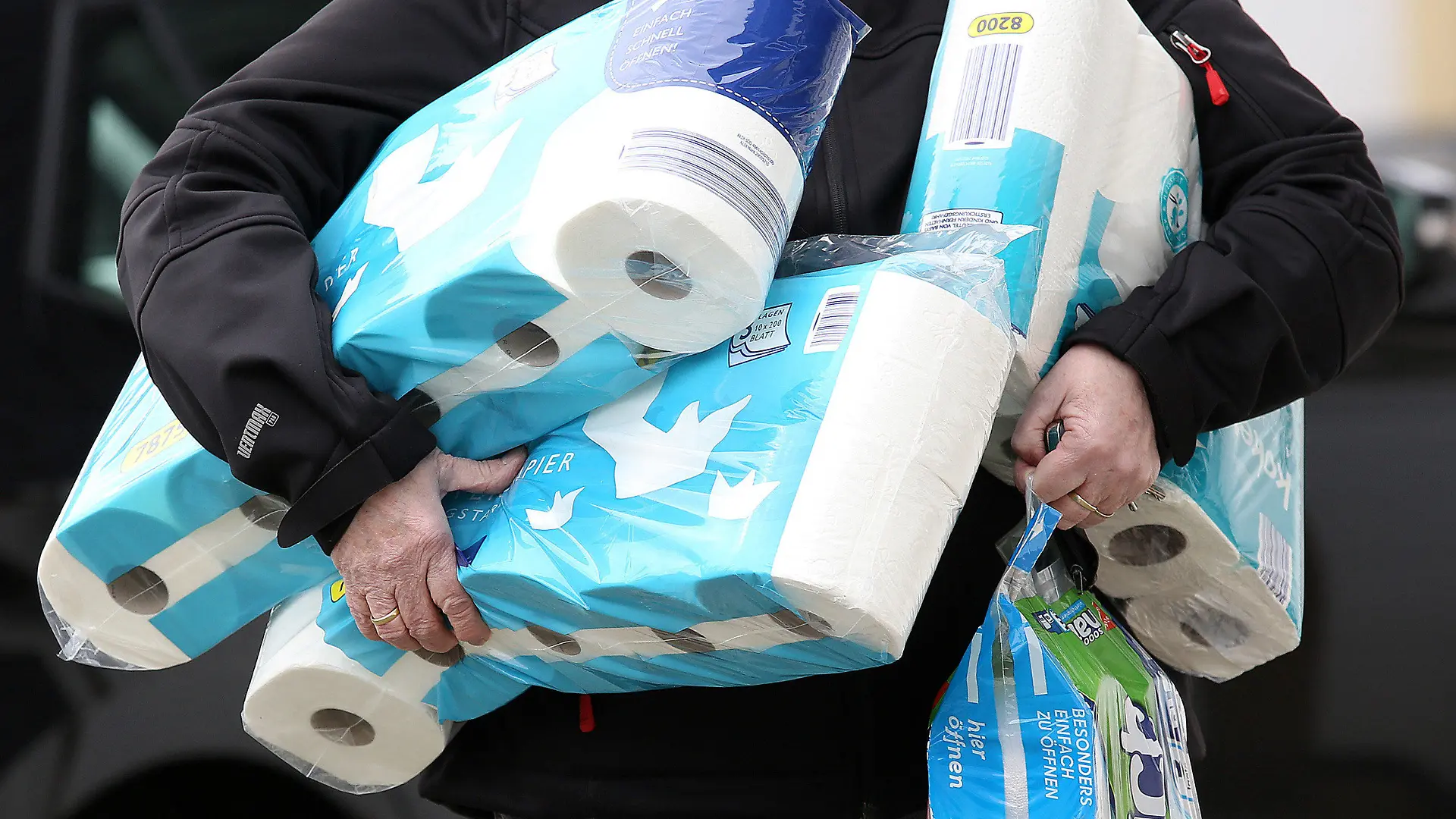 ARCHIV - 18.03.2020, Nordrhein-Westfalen, Siegen: Ein Mann trägt eingekauftes Toilettenpapier und Küchenrollen aus einem Supermarkt. Solche Artikel dürften in Kürze teurer werden. Ein großer Hersteller hat drastische Preiserhöhungen angekündigt. (Zu dpa "Klopapier-Hersteller kündigt drastische Preiserhöhung an") Foto: Rene Traut/dpa +++ dpa-Bildfunk +++