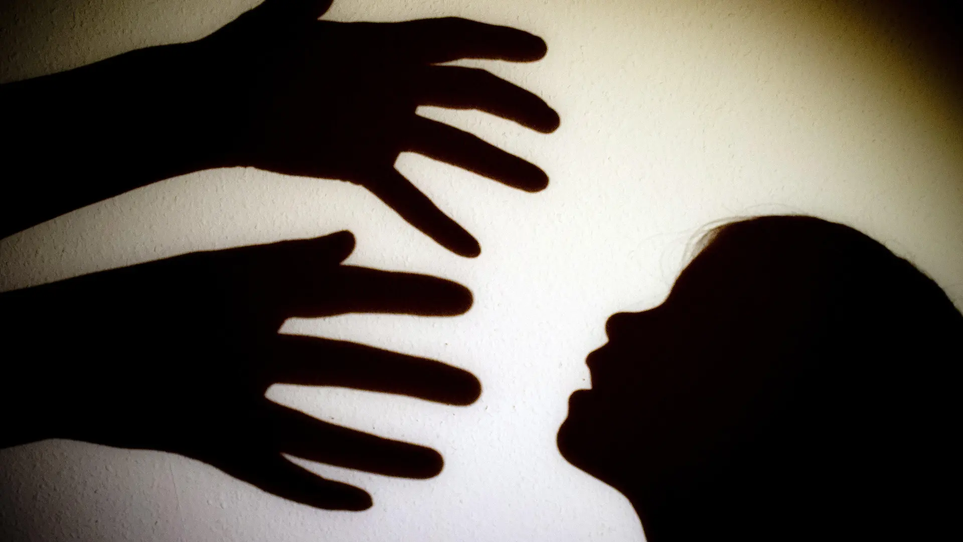 ARCHIV - 12.01.2014, Brandenburg, Frankfurt (Oder): ILLUSTRATION - Schatten von Händen einer erwachsenen Person und dem Kopf eines Kindes an einer Wand eines Zimmers. Jugendmediziner haben einen besseren Schutz für Kinder vor Gewalt und eine stärkere Lobby für die Kleinsten gefordert. Tagtäglich würden Jungen und Mädchen Opfer von Vernachlässigung, Missbrauch und Misshandlung, sagte Tanja Brüning, Leiterin der Medizinischen Kinderschutzambulanz an der Vestischen Kinder- und Jugendklinik Datteln der dpa am Rande einer Expertenveranstaltung in Lünen. Foto: Patrick Pleul/dpa-Zentralbild/dpa +++ dpa-Bildfunk +++