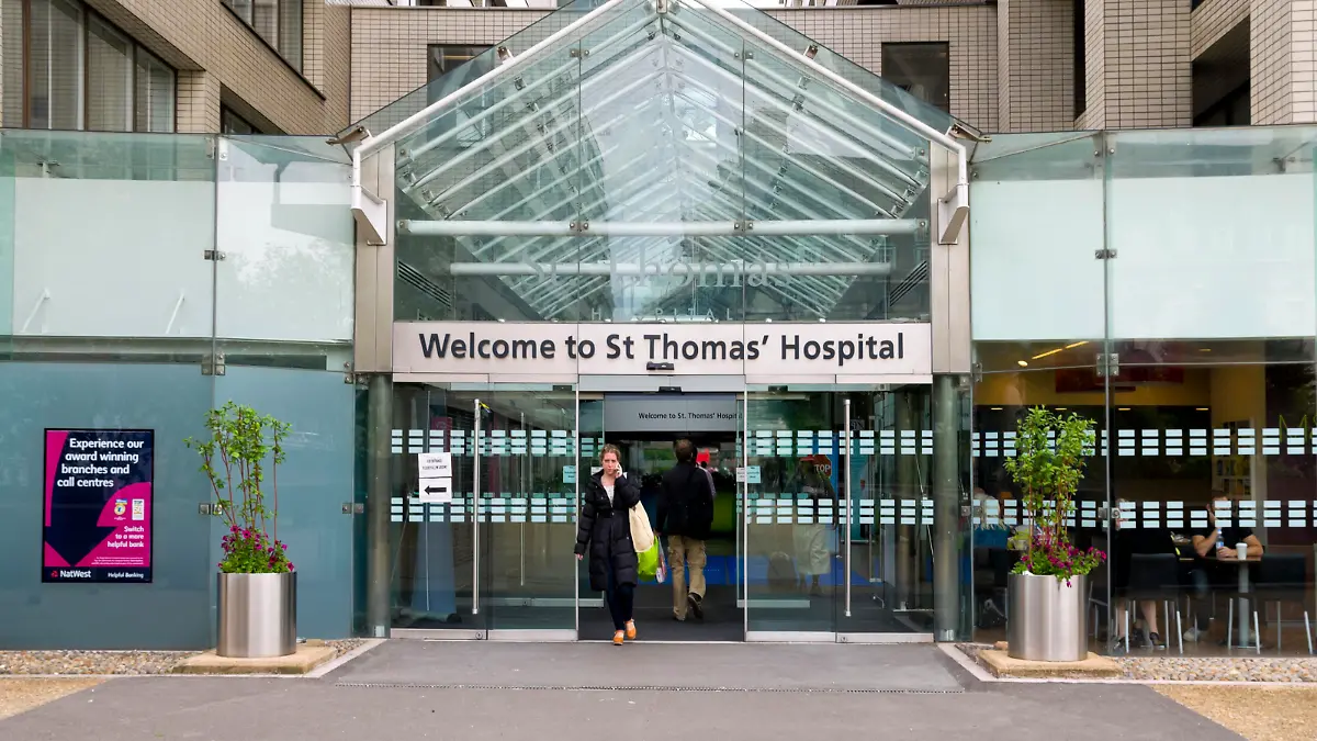 "London, England - June 9, 2012: : People entering and leaving St Thomas Hospital in London. St Thomas is a very ancient hospital foundation, named after St Thomas aBecket, though it is no longer on its original site. Florence Nightingale set up her nursing school at the hospital prior to its move to Lambeth. It is now a very large NHS teaching hospital on the south bank of the River Thames and some of the wards provide a view of the Houses of Parliament across the river."