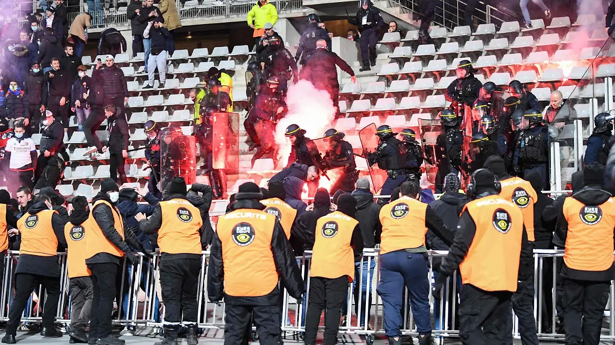 17.12.2021, Frankreich, Paris: Französische Polizisten greifen ein, als Fans im Parise Charlety-Stadion Fackeln entzünden. In Frankreich haben erneut Zuschauerkrawalle für den Abbruch eines Fußballspiels unter Beteiligung von Olympique Lyon gesorgt. (zu dpa: «Wieder Fußballspiel in Frankreich wegen Fankrawallen abgebrochen») Foto: Bertrand Guay/AFP/dpa +++ dpa-Bildfunk +++