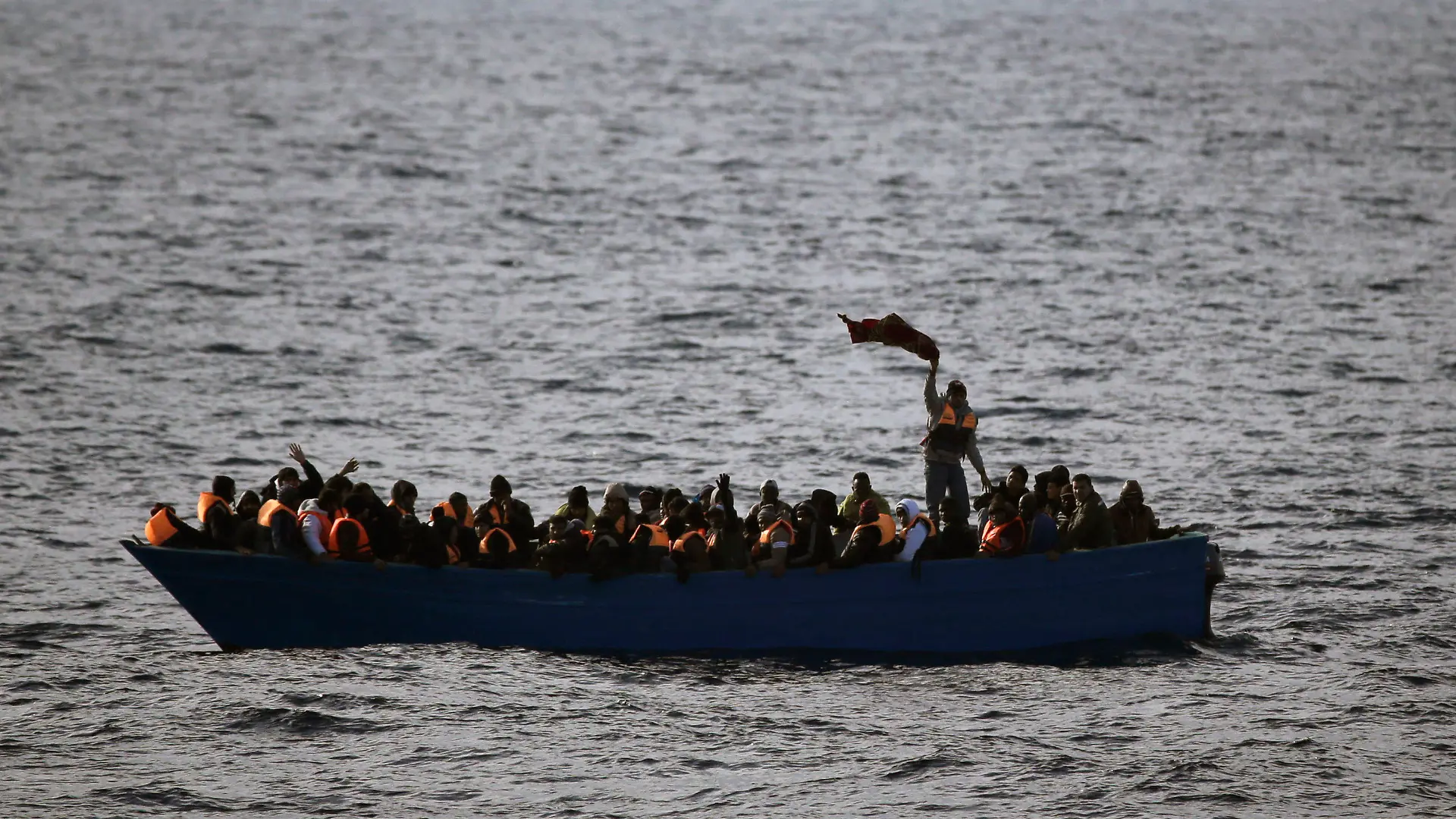 ARCHIV - 03.02.2017, ---: Flüchtlinge aus Afrika rufen auf dem Mittelmeer in einem Boot um Hilfe. (ILLUSTRATION zu dpa "115 Migranten nach Bootsunglück im Mittelmeer vermisst") Foto: Emilio Morenatti/AP/dpa +++ dpa-Bildfunk +++
