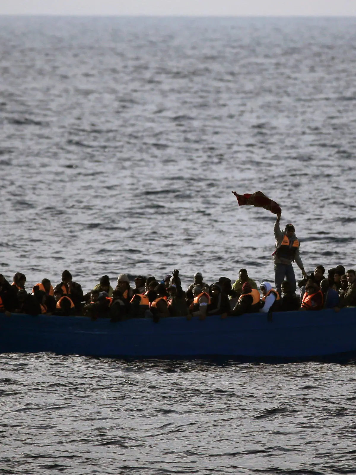 ARCHIV - 03.02.2017, ---: Flüchtlinge aus Afrika rufen auf dem Mittelmeer in einem Boot um Hilfe. (ILLUSTRATION zu dpa "115 Migranten nach Bootsunglück im Mittelmeer vermisst") Foto: Emilio Morenatti/AP/dpa +++ dpa-Bildfunk +++