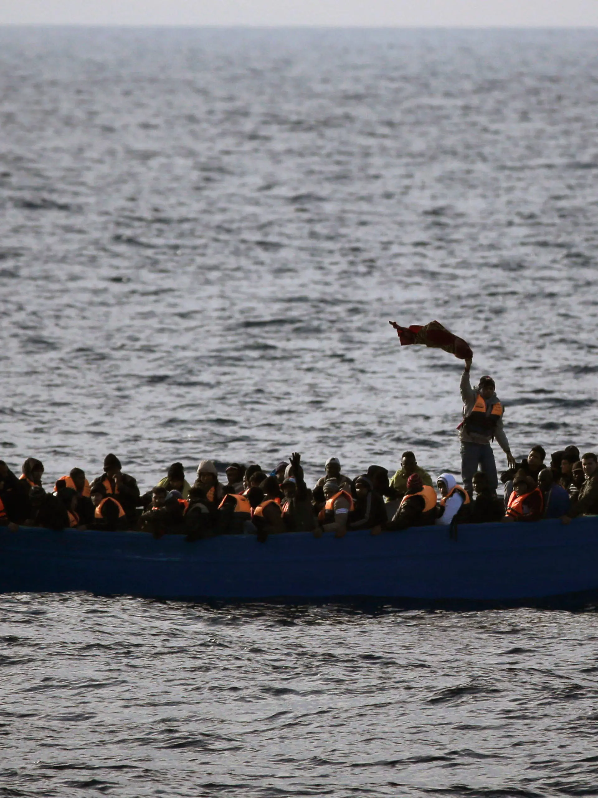 ARCHIV - 03.02.2017, ---: Flüchtlinge aus Afrika rufen auf dem Mittelmeer in einem Boot um Hilfe. (ILLUSTRATION zu dpa "115 Migranten nach Bootsunglück im Mittelmeer vermisst") Foto: Emilio Morenatti/AP/dpa +++ dpa-Bildfunk +++