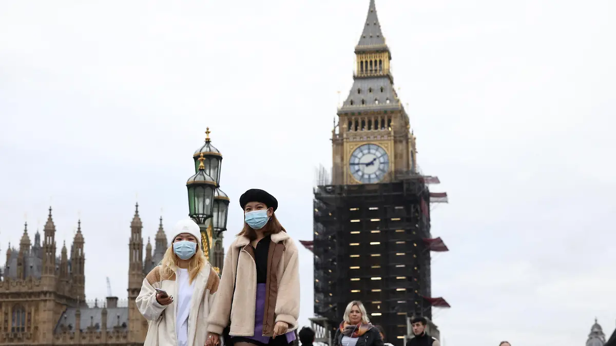 People wearing protective face masks walk over Westminster Bridge in front of the Elizabeth Tower, more commonly known as Big Ben, in London, Britain, December 15, 2021. REUTERS/Henry Nicholls