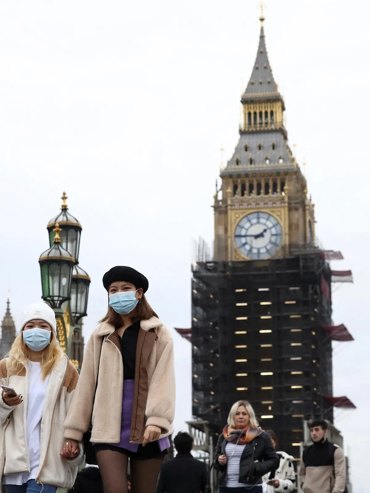People wearing protective face masks walk over Westminster Bridge in front of the Elizabeth Tower, more commonly known as Big Ben, in London, Britain, December 15, 2021. REUTERS/Henry Nicholls