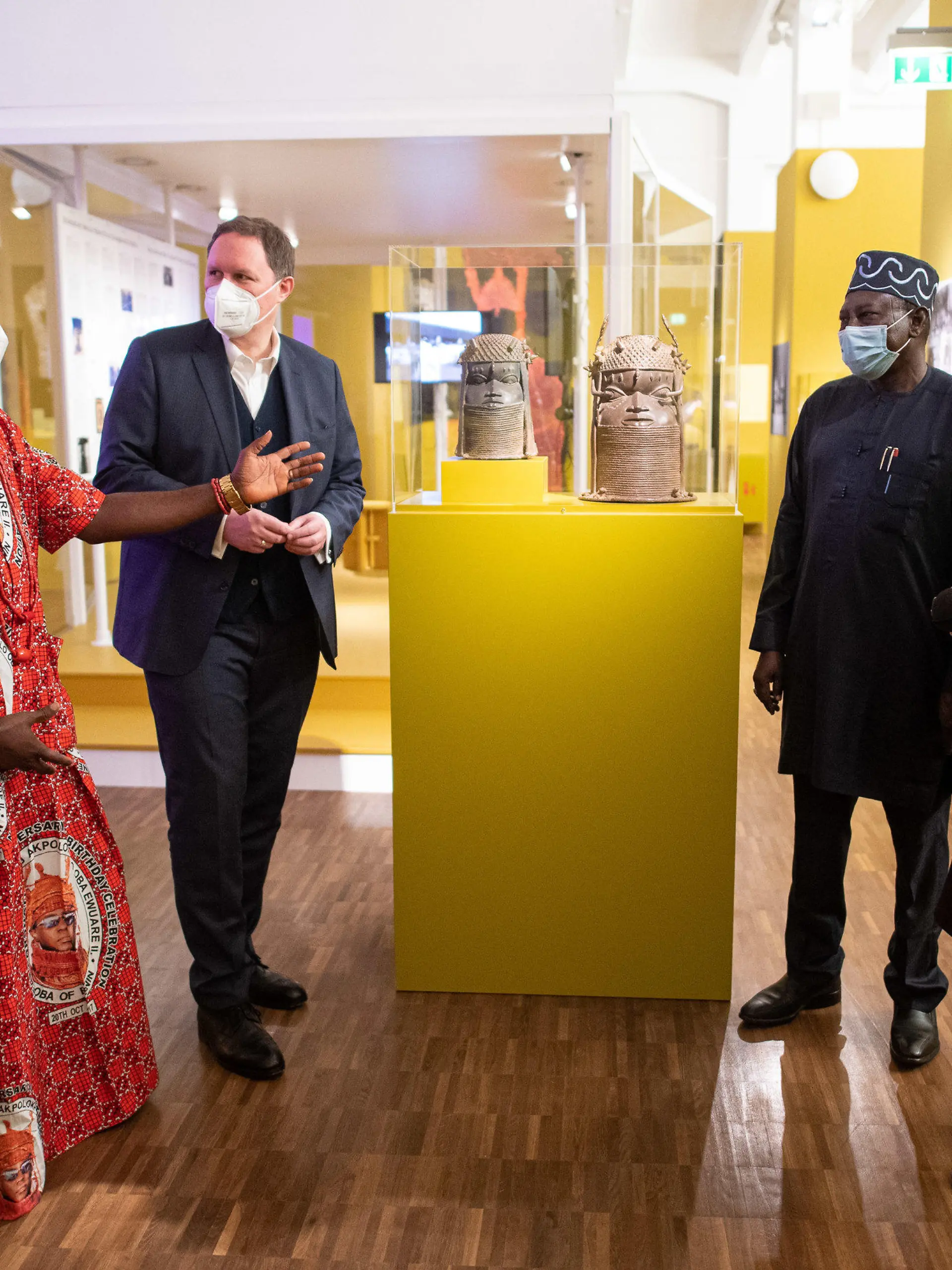 16.12.2021, Hamburg: Osaisonor Godfrey Ekhator-Obogie (l-r), Mitglied des kuratorischen Teams, Carsten Brosda (SPD), Kultursenator von Hamburg, Abba Isa Tijani, Generaldirektor der National Commission for Museums and Monuments, und Barbara Plankensteiner, Direktorin des Museums am Rothenbaum stehen um zwei Gedenkköpfe eines Königs aus einer Unbekannten Werkstatt der Bronzegießergilde Igun Eronmwon (Königreich Benin, Nigeria, 19. Jahrhundert) in der Ausstellung «Benin. Geraubte Geschichte» im Museum am Rothenbaum. (zu dpa «Museum am Rothenbaum zeigt «Benin-Bronzen» vor Rückgabe») Foto: Daniel Reinhardt/dpa - ACHTUNG: Nur zur redaktionellen Verwendung im Zusammenhang mit einer Berichterstattung über die Ausstellung und nur mit vollständiger Nennung des vorstehenden Credits +++ dpa-Bildfunk +++