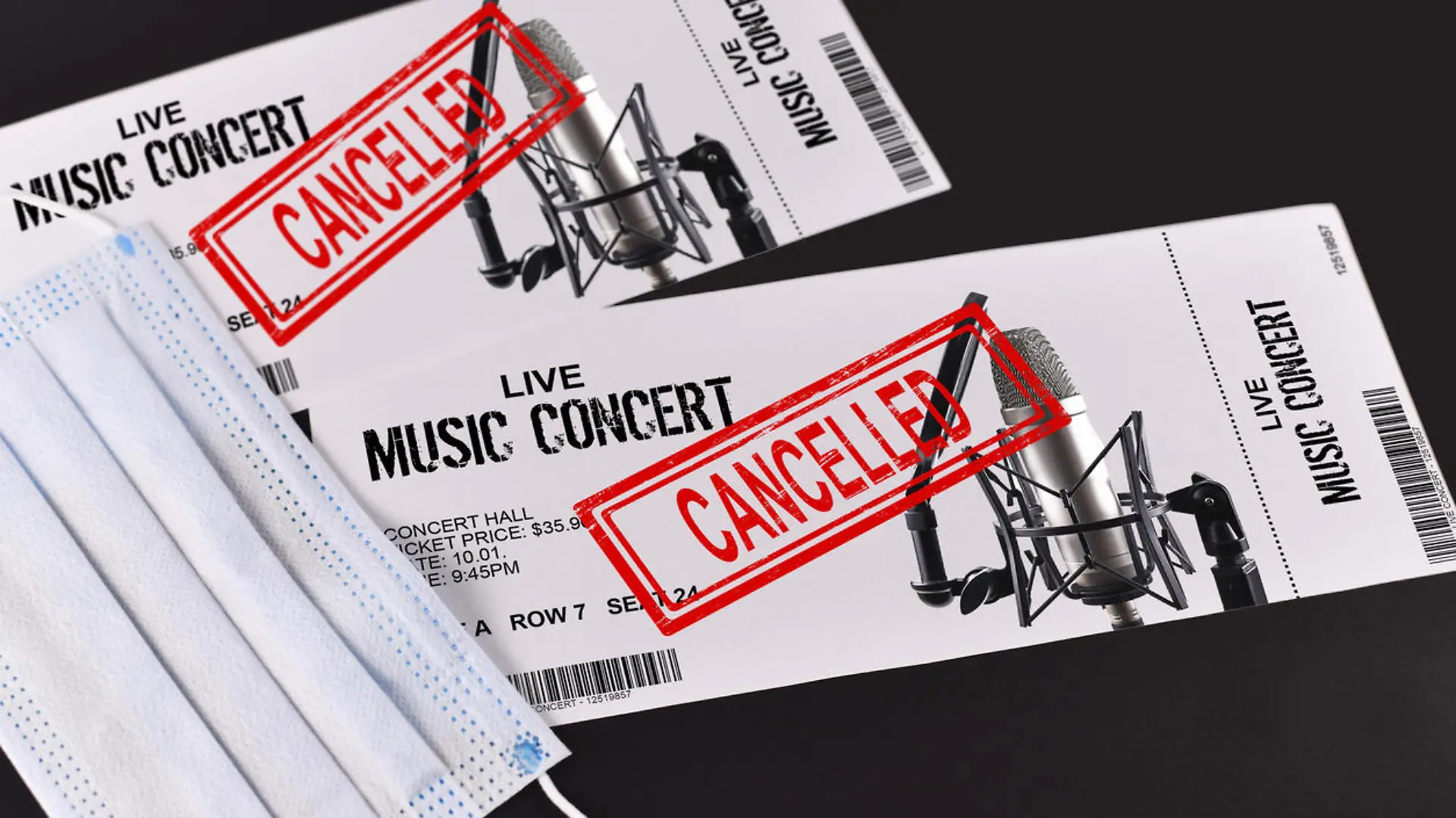 Concept for cancelled entertainment events during Corona virus pandemic with concert tickets and red 'cancelled' stamp on them and face mask