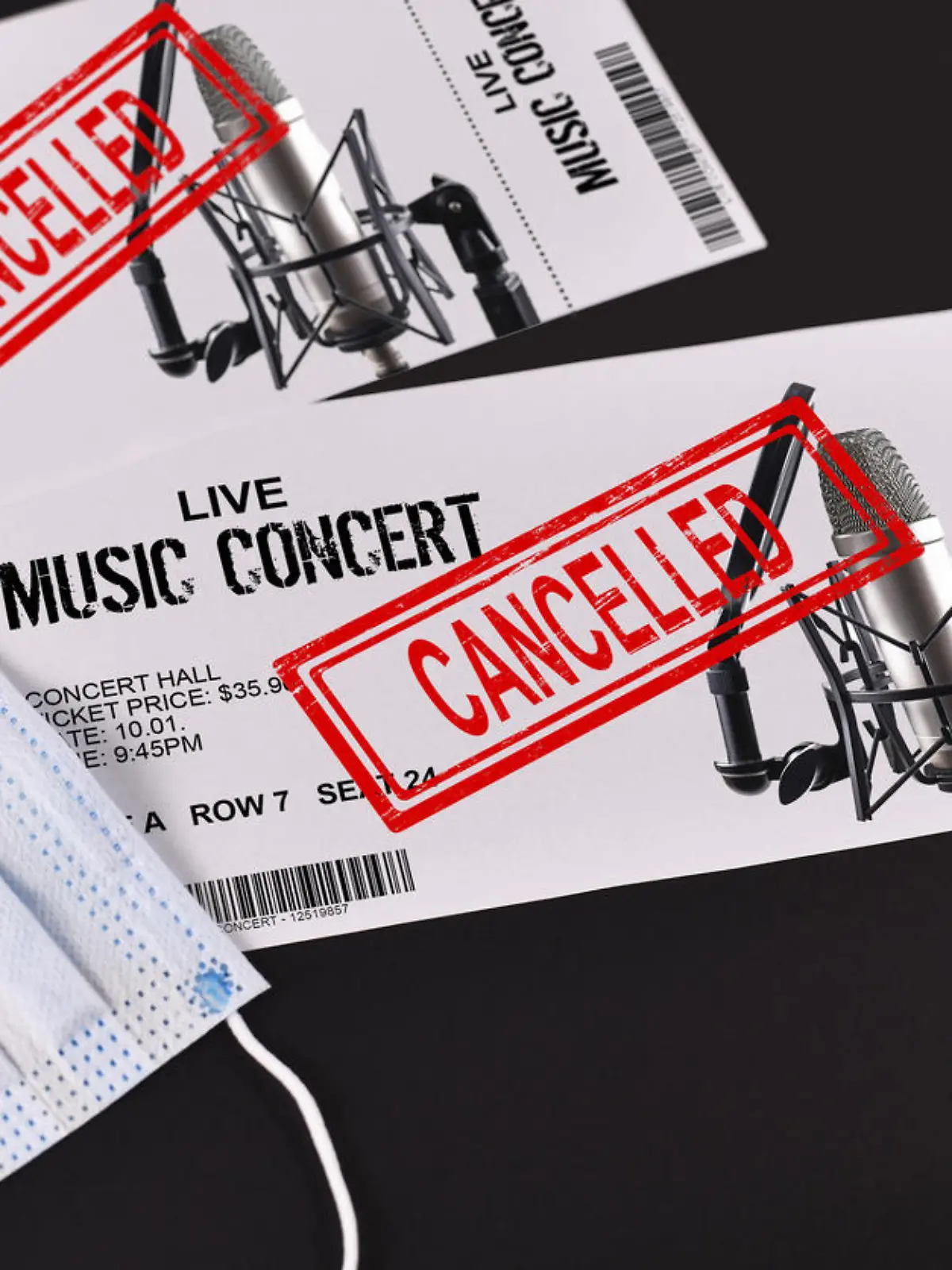 Concept for cancelled entertainment events during Corona virus pandemic with concert tickets and red 'cancelled' stamp on them and face mask