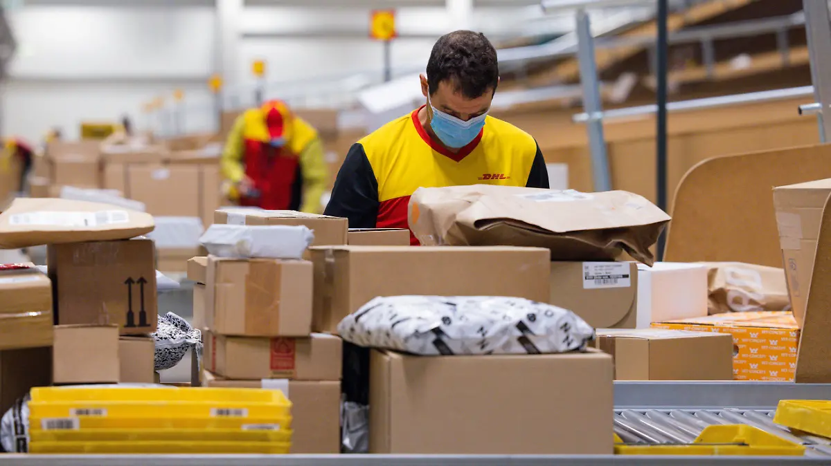 Paketzusteller sortieren und räumen in einer Zustellbasis von Deutsche Post DHL Pakete in ein Zustellfahrzeug.