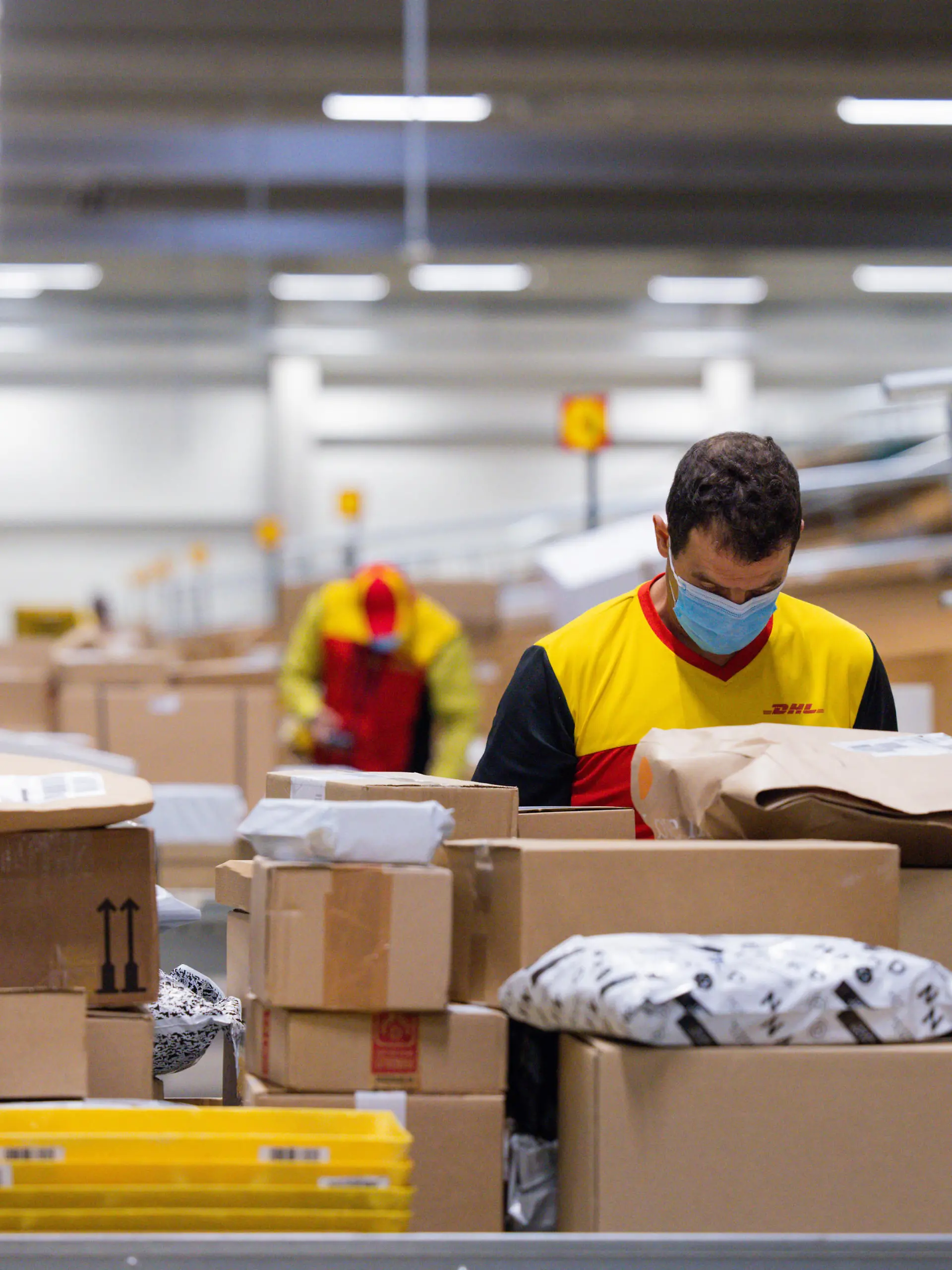 Paketzusteller sortieren und räumen in einer Zustellbasis von Deutsche Post DHL Pakete in ein Zustellfahrzeug.
