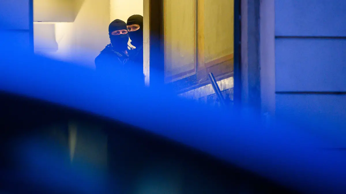 15.12.2021, Sachsen, Dresden: Polizisten stehen während einer Razzia in einem Haus im Stadtteil Pieschen. Nach Drohungen gegen Sachsens Ministerpräsidenten Kretschmer auf Telegram durchsucht die Polizei in Dresden mehrere Objekte. Beteiligt seien auch Spezialkräfte des Landeskriminalamts (LKA), da Äußerungen einzelner Mitglieder der Telegram-Gruppe den Verdacht nahe legten, dass diese im Besitz von scharfen Waffen und Armbrüsten sein könnten, teilte die Polizei auf Twitter mit. Foto: Robert Michael/dpa-Zentralbild/dpa +++ dpa-Bildfunk +++