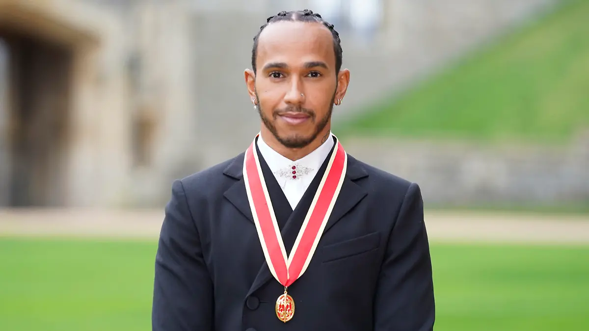 Lewis Hamilton poses for the media after he was made a Knight Bachelor by Britain's Prince Charles during a investiture ceremony at Windsor Castle in Windsor, England, Wednesday, Dec. 15, 2021. (Andrew Matthews/Pool Photo via AP)
