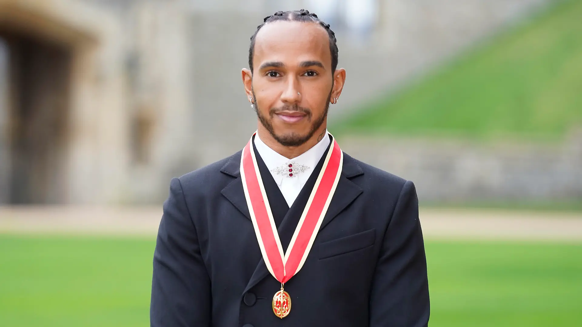 Lewis Hamilton poses for the media after he was made a Knight Bachelor by Britain's Prince Charles during a investiture ceremony at Windsor Castle in Windsor, England, Wednesday, Dec. 15, 2021. (Andrew Matthews/Pool Photo via AP)