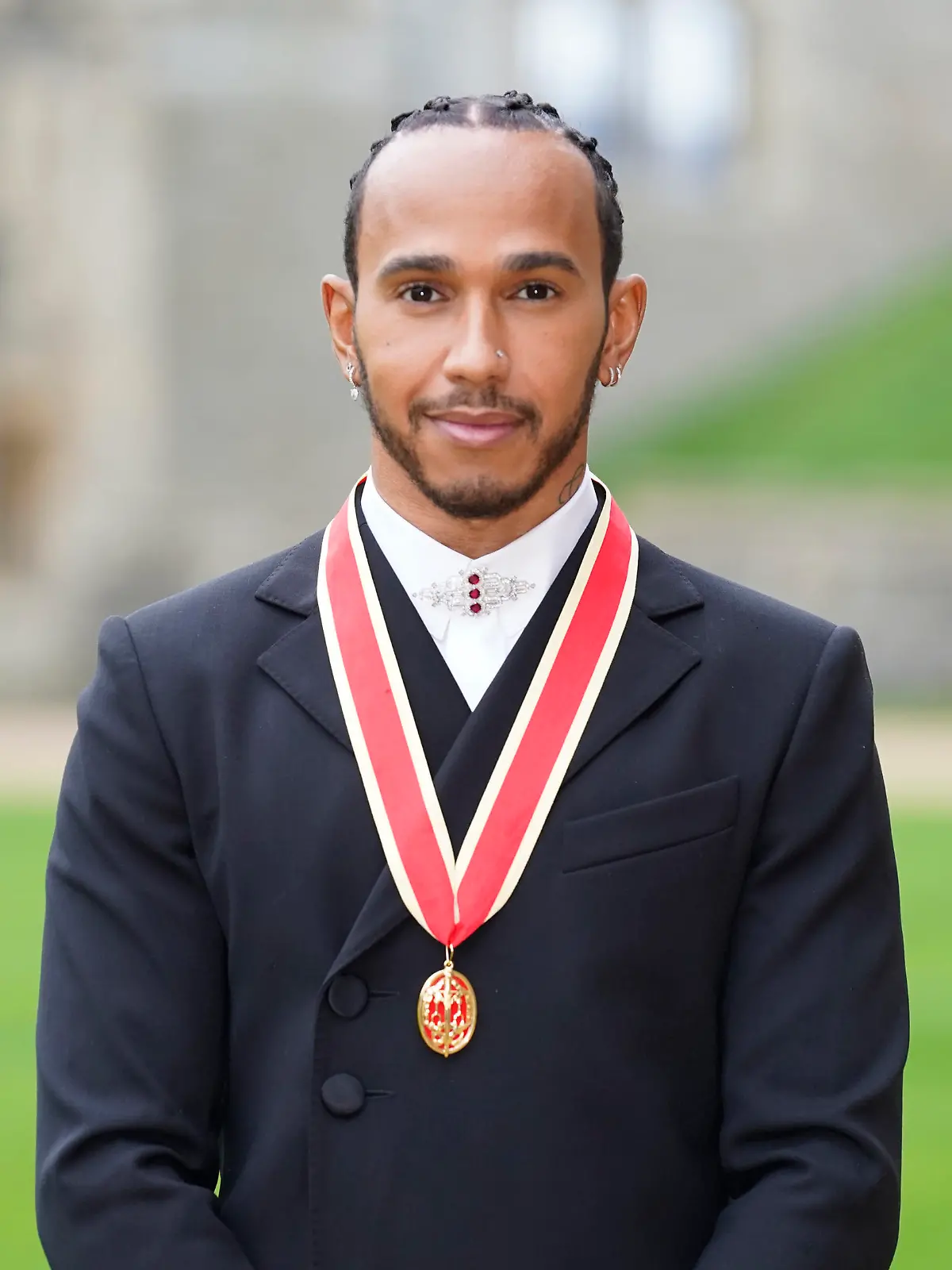 Lewis Hamilton poses for the media after he was made a Knight Bachelor by Britain's Prince Charles during a investiture ceremony at Windsor Castle in Windsor, England, Wednesday, Dec. 15, 2021. (Andrew Matthews/Pool Photo via AP)