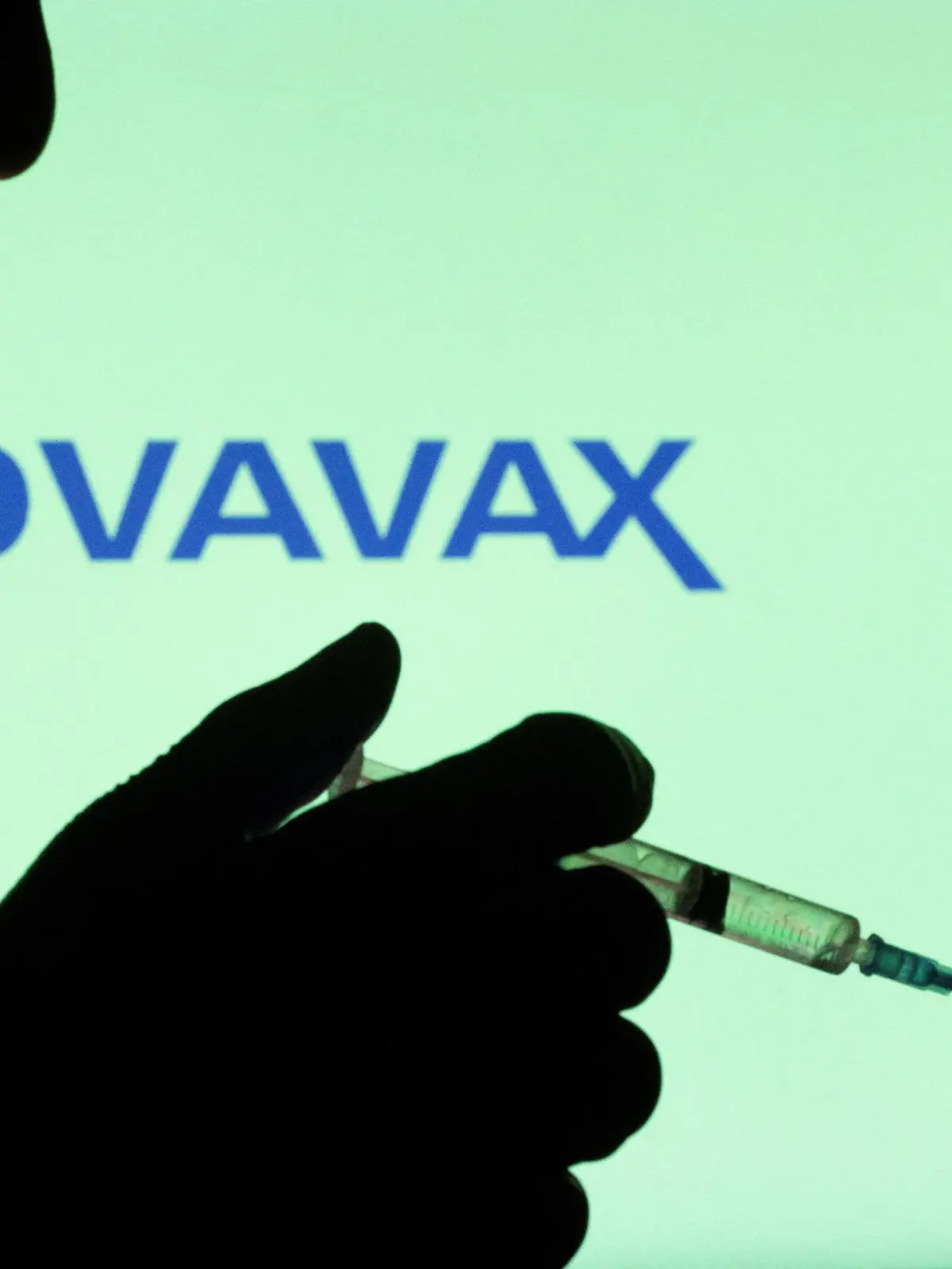 People pose with syringe with needle in front of displayed Novavax logo in this illustration taken, December 11, 2021. REUTERS/Dado Ruvic/Illustration