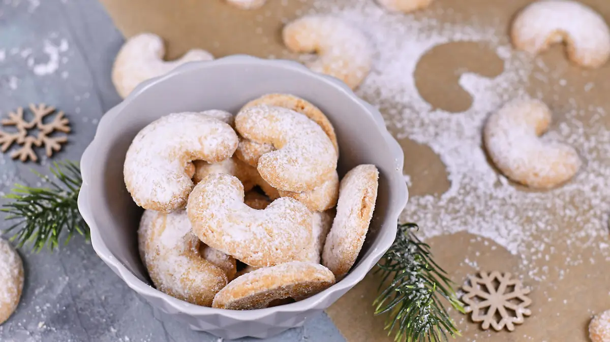 Seasonal crescent shaped christmas cookies called 'Vanillekipferl', a traditional Austrian or German Christmas biscuits with nuts and icing sugar in bowl