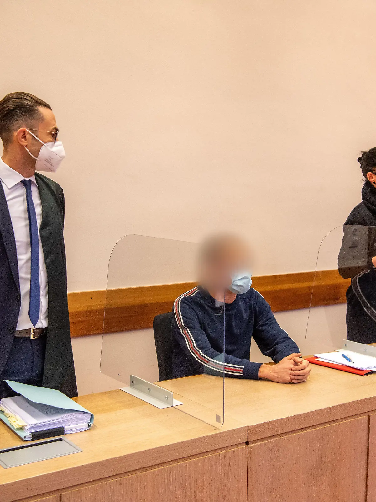 14.12.2021, Nordrhein-Westfalen, Detmold: Der Angeklagte (M) sitzt zwischen seinen Anwälten im Prozess um fahrlässige Körperverletzung durch eine fehlerhafte Zahn-Behandlung. Die Staatsanwaltschaft wirft dem 44-jährigen Angeklagten vor, eine damals 7-Jährige im September 2017 bei einer Zahnarztbehandlung falsch intubiert zu haben. Seit der Narkose, bei der der Sauerstoff in die Speise- und nicht in die Luftröhre geleitet worden sein soll, hatte das Kind einen irreparablen Hirnschaden. Den Fehler bei der Behandlung mehrerer Milchzähne soll der Mediziner zu spät erkannt haben. Der 44-Jährige streitet dies ab und geht von einer Verkrampfung der Atemwege aus (Bronchospasmus). Foto: Lino Mirgeler/dpa - ACHTUNG: Person(en) wurde(n) aus rechtlichen Gründen gepixelt +++ dpa-Bildfunk +++
