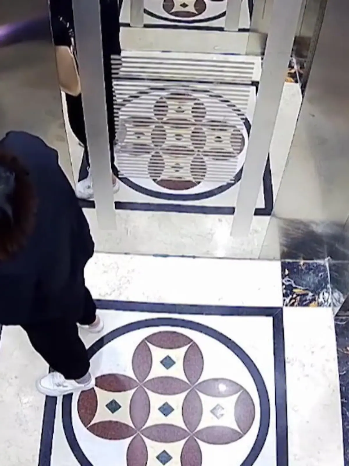In China hat ein Aufzug mit zwei Türen diese Frau überfordert. Verzweifelt hämmert sie an die Tür, betätigt noch einmal den Knopf – und merkt nicht, dass sie damit die Tür hinter sich öffnet.