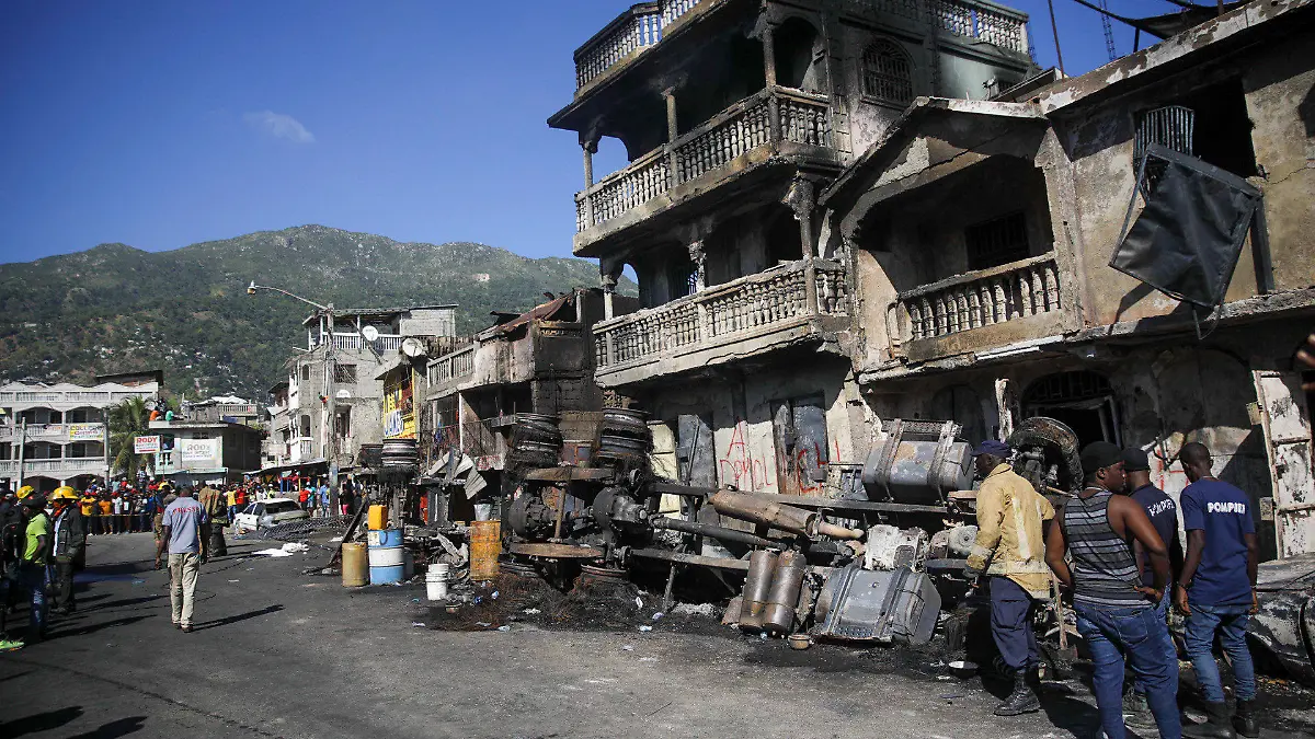 dpatopbilder - 14.12.2021, Haiti, Cap-Haitien: Feuerwehrleute stehen neben den Überresten eines mit Benzin beladenen Lastwagens, der in Brand geriet und explodierte. Bei der Explosion seien mindestens 60 Menschen getötet worden, sagte der stellvertretende Bürgermeister Patrick Almonor am 14.12.21 im Radiosender RFM. Foto: Odelyn Joseph/AP/dpa +++ dpa-Bildfunk +++