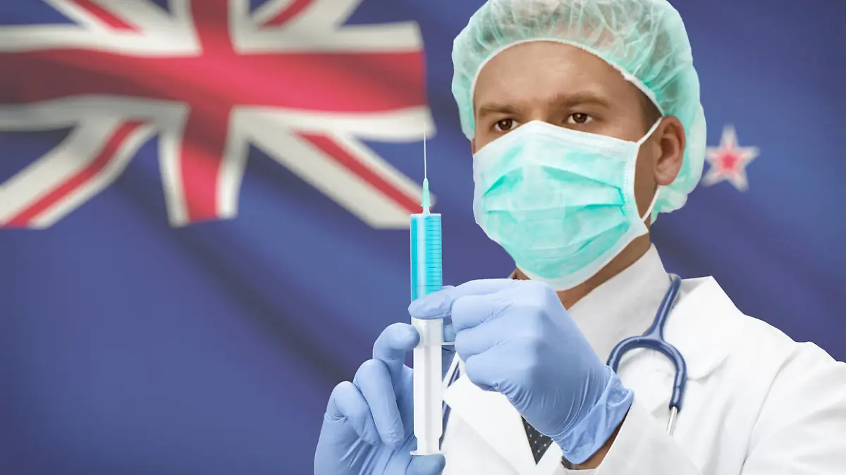 Doctor with syringe in hands and flag on background - New Zealand