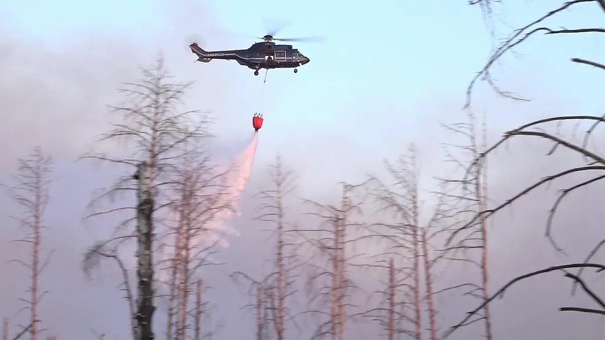 dpatopbilder - 01.06.2023, Brandenburg, Jüterbog: Ein Löschhubschrauber wirft Wasser ab über einem Waldbrand in einem munitionsbelasteten Gebiet bei Jüterbog (Landkreis Teltow-Fläming). Der Waldbrand hat sich trotz des Löscheinsatzes aus der Luft auf rund 27 Hektar ausgebreitet. Foto: Cevin Dettlaff/dpa +++ dpa-Bildfunk +++