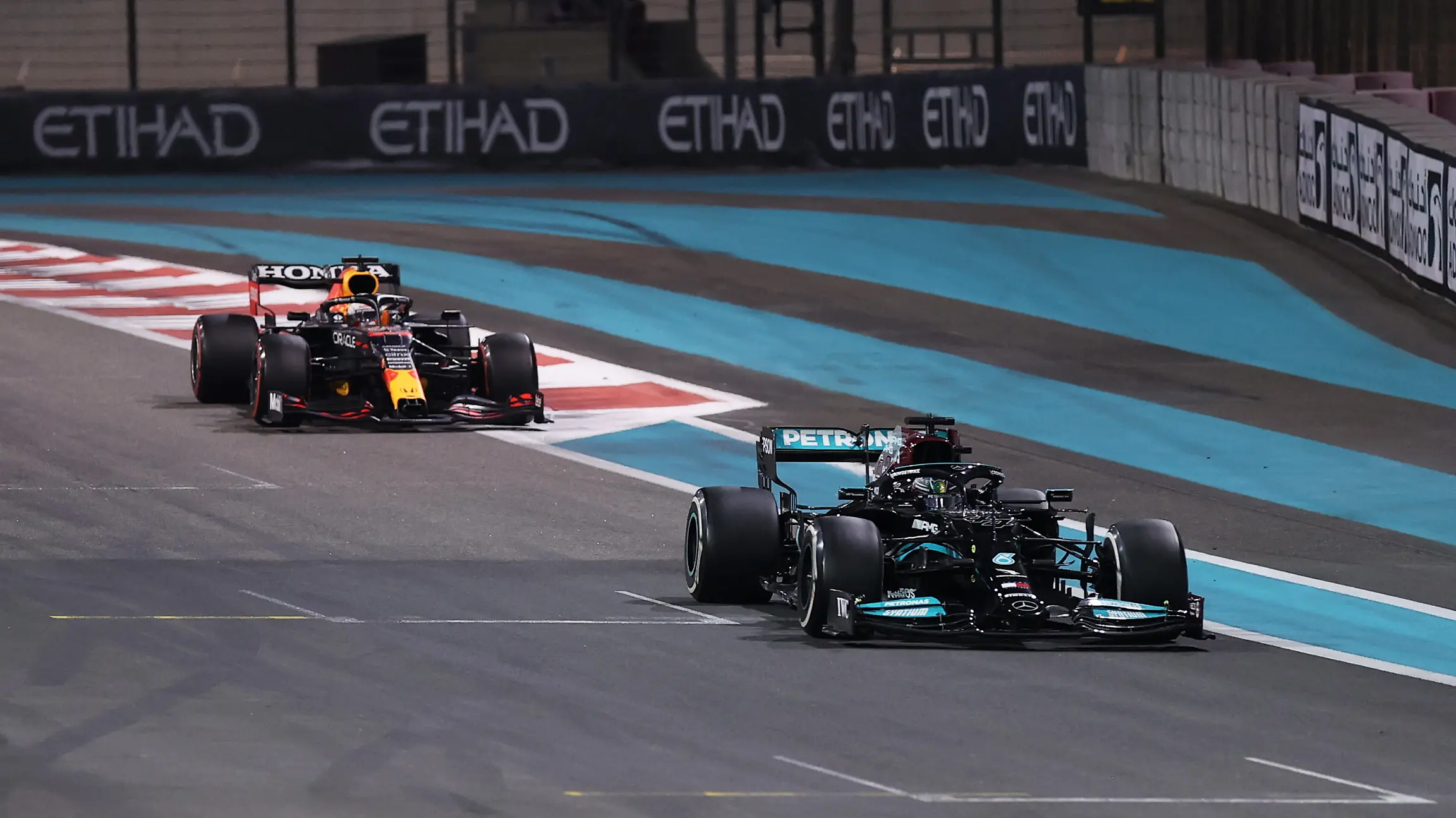 ABU DHABI, UNITED ARAB EMIRATES - DECEMBER 12: Lewis Hamilton of Great Britain driving the (44) Mercedes AMG Petronas F1 Team Mercedes W12 leads Max Verstappen of the Netherlands driving the (33) Red Bull Racing RB16B Honda at the safety car restart during the F1 Grand Prix of Abu Dhabi at Yas Marina Circuit on December 12, 2021 in Abu Dhabi, United Arab Emirates. (Photo by Lars Baron/Getty Images)