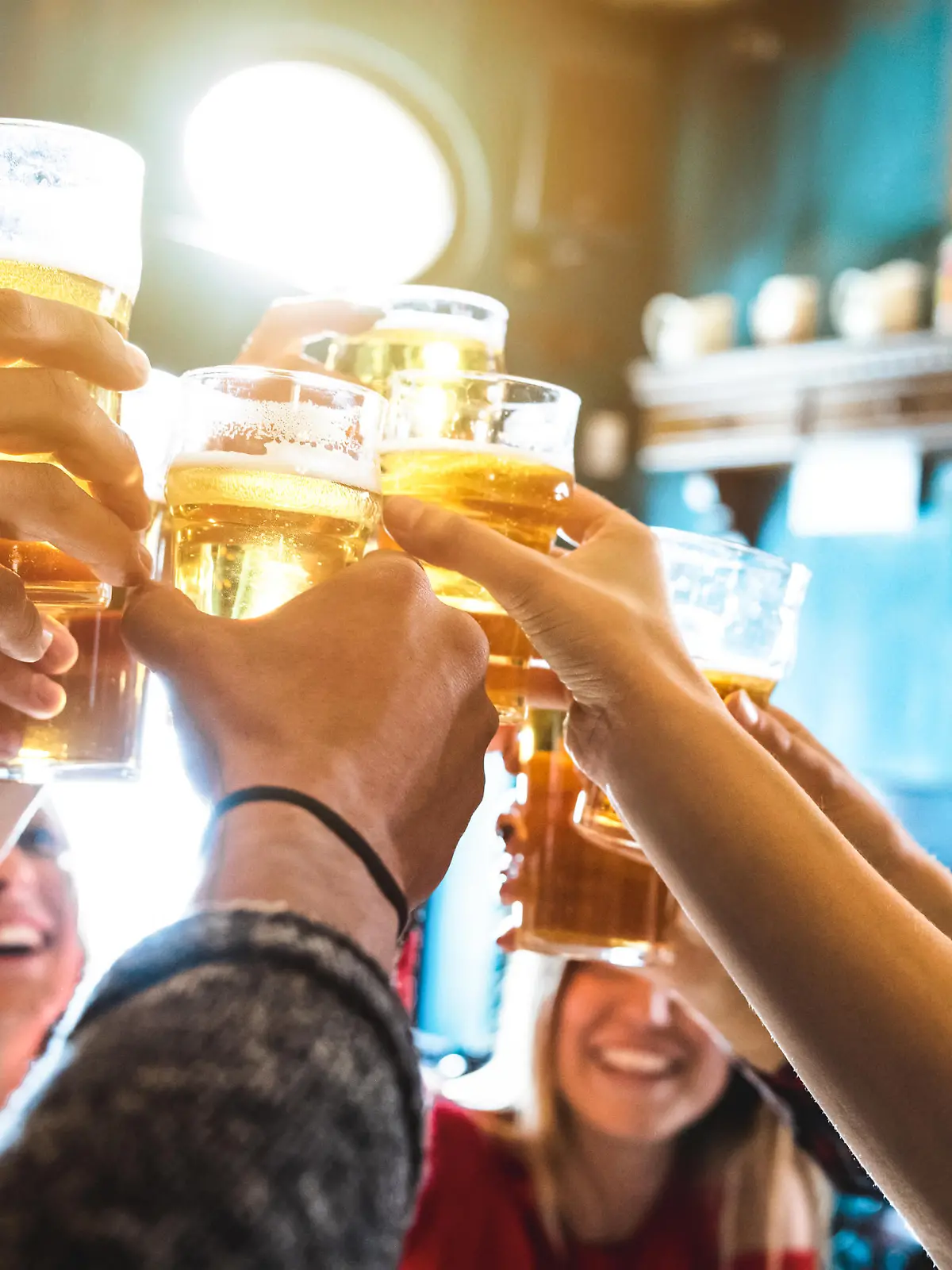 Group of happy friends drinking and toasting beer at brewery bar restaurant - Friendship concept with young people having fun together at cool vintage pub - Focus on middle pint glass - High iso image