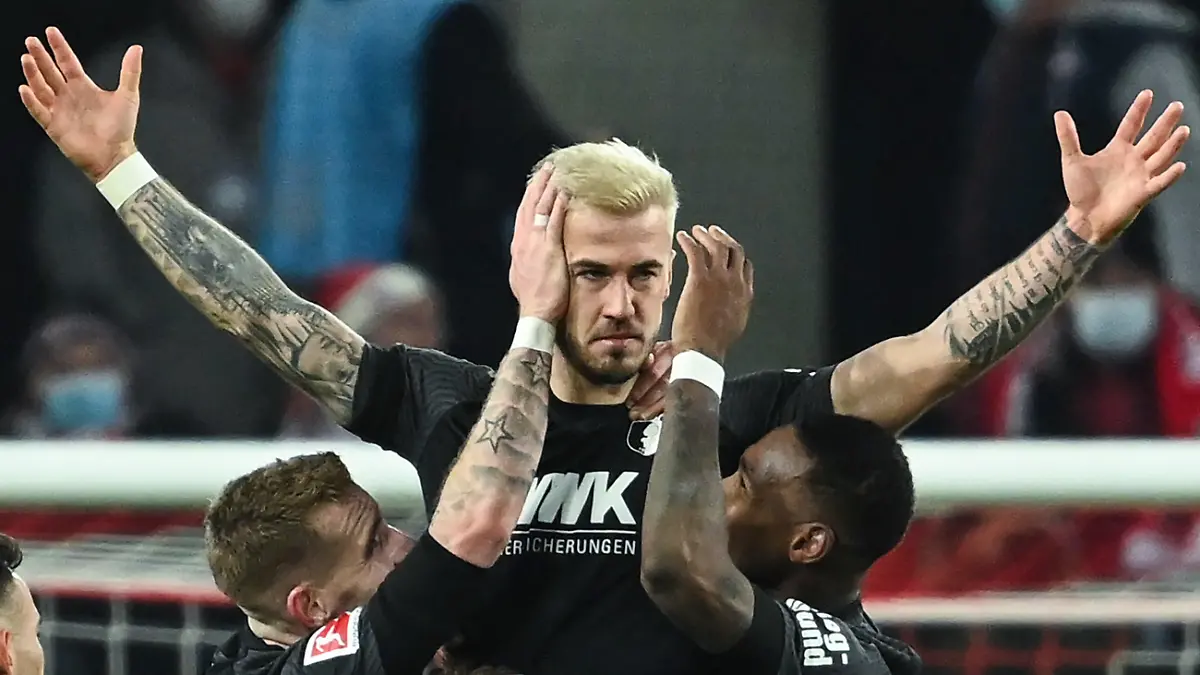 dpatopbilder - 10.12.2021, Nordrhein-Westfalen, Köln: Fußball: Bundesliga, 1. FC Köln - FC Augsburg, 15. Spieltag im RheinEnergieStadion. Augsburgs Niklas Dorsch (M) feiert mit Teamkameraden das Tor zum 0:2. . Foto: Federico Gambarini/dpa - WICHTIGER HINWEIS: Gemäß den Vorgaben der DFL Deutsche Fußball Liga bzw. des DFB Deutscher Fußball-Bund ist es untersagt, in dem Stadion und/oder vom Spiel angefertigte Fotoaufnahmen in Form von Sequenzbildern und/oder videoähnlichen Fotostrecken zu verwerten bzw. verwerten zu lassen. +++ dpa-Bildfunk +++
