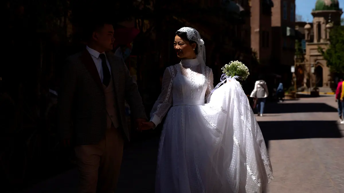 A woman in a bridal outfit walks as she poses for wedding photos in the old city in Kashgar in western China's Xinjiang Uyghur Autonomous Region, as seen during a government organized trip for foreign journalists, Monday, April 19, 2021. A human rights group is appealing to the United Nations to investigate allegations China's government is committing crimes against humanity in the Xinjiang region. Human Rights Watch cited reports of the mass detention of Muslims, a crackdown on religious practices and other measures against minorities in the northwestern region. (AP Photo/Mark Schiefelbein)