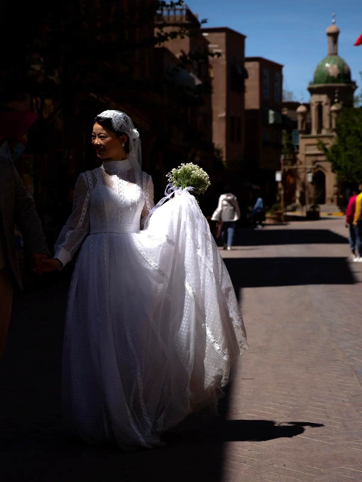 A woman in a bridal outfit walks as she poses for wedding photos in the old city in Kashgar in western China's Xinjiang Uyghur Autonomous Region, as seen during a government organized trip for foreign journalists, Monday, April 19, 2021. A human rights group is appealing to the United Nations to investigate allegations China's government is committing crimes against humanity in the Xinjiang region. Human Rights Watch cited reports of the mass detention of Muslims, a crackdown on religious practices and other measures against minorities in the northwestern region. (AP Photo/Mark Schiefelbein)