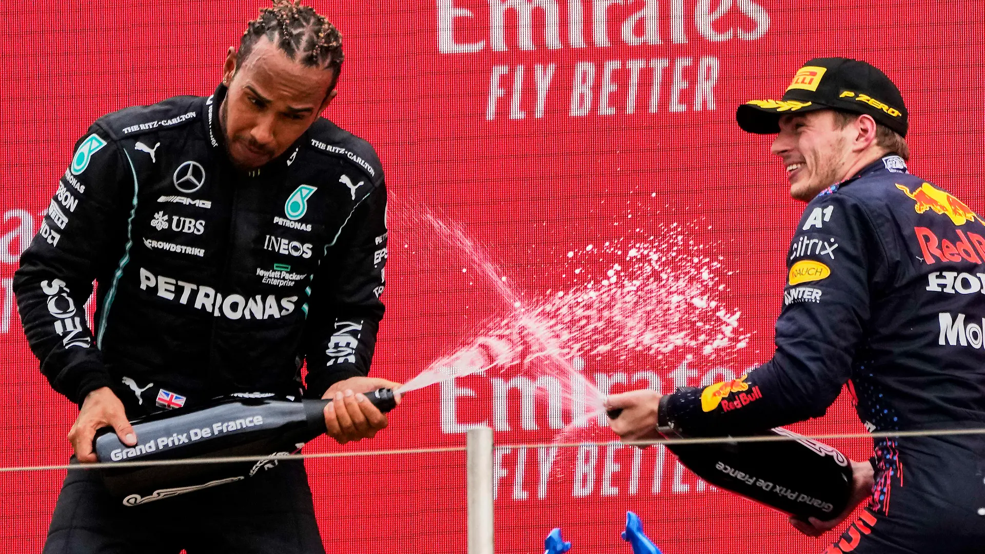 ARCHIV - 20.06.2021, Frankreich, Le Castellet: Motorsport: Formel-1-Weltmeisterschaft, Großer Preis von Frankreich. Sieger Max Verstappen (r) aus den Niederlanden vom Team Red Bull Racing und der Zweitplatzierte Lewis Hamilton aus Großbritannien vom Team Mercedes lassen auf dem Podium Champagner aus einer Flasche spritzen. (zu "Darüber wird gesprochen in der Formel-1-Saison 2021 - von A bis Z") Foto: Francois Mori/AP/dpa +++ dpa-Bildfunk +++