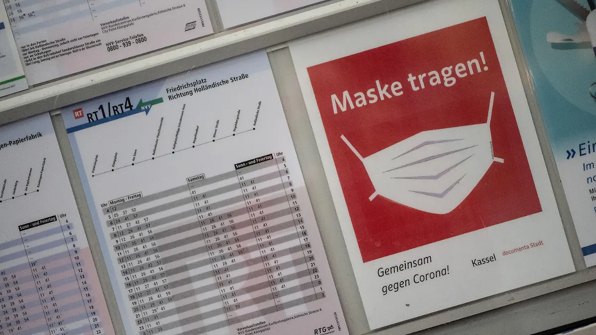 25.11.2021, Hessen, Kassel: Ein Schild "Maske tragen" ist neben Fahrplänen an einer Haltestelle zu sehen.  In allen Bussen und Bahnen der Kasseler Verkehrs-Gesellschaft (KVG) gilt  entsprechend dem Corona-Infektionsschutzgesetz nicht nur Maskenpflicht, sondern außerdem die 3G-Regel. Foto: Swen Pförtner/dpa +++ dpa-Bildfunk +++