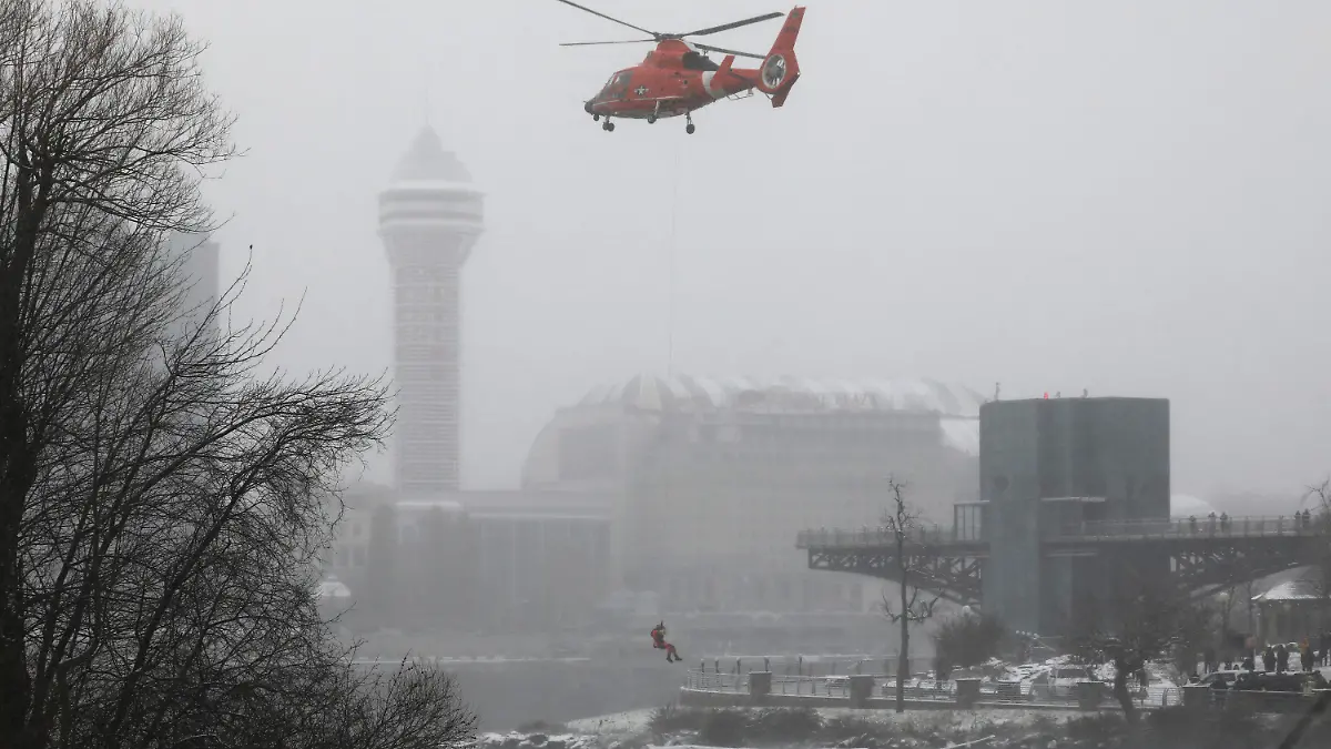 A U.S. Coast Guard rescue diver is lowered toward the vehicle lodged in the water at the brink of Niagara Falls, Wednesday, Dec. 8, 2021. (Derek Gee/Buffalo News via AP)
