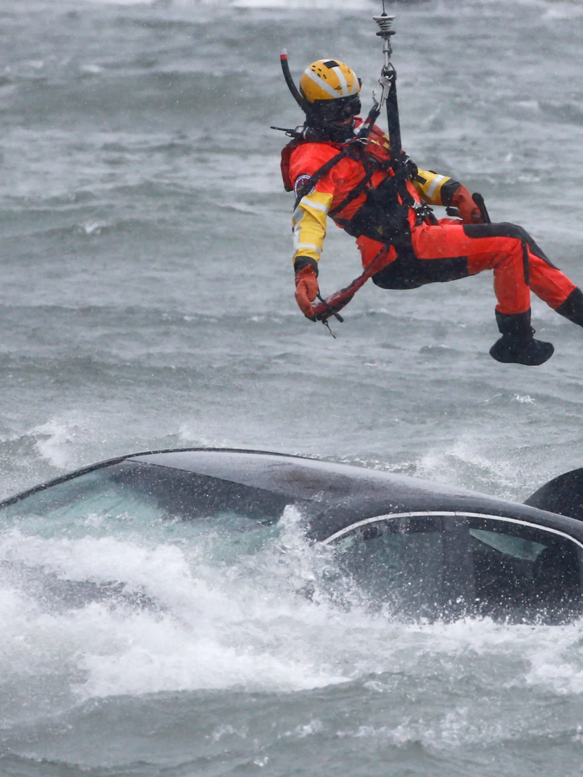 A U.S. Coast Guard diver is lowered from a hovering helicopter to pull a body from a submerged vehicle stuck in rushing rapids just yards from the brink of Niagara Falls, Wednesday, Dec. 8, 2021, in Niagara Falls, N.Y. (AP Photo/ Jeffrey T. Barnes)
