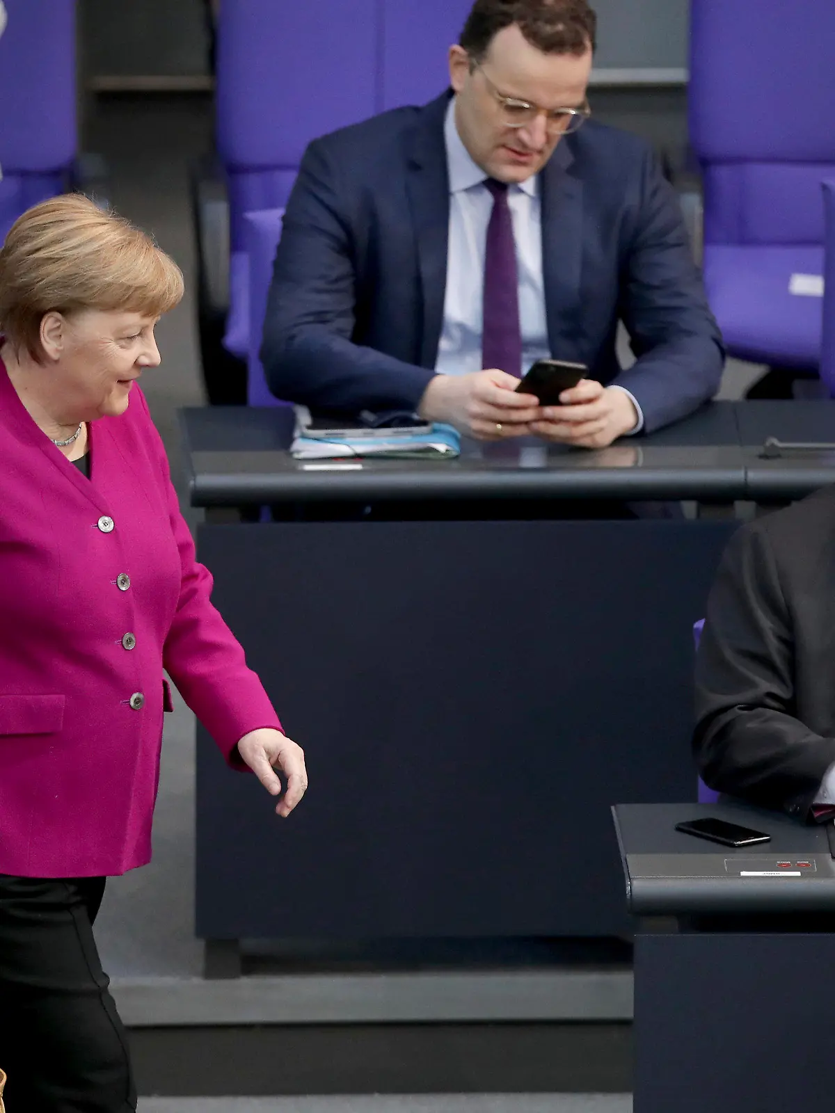 German Chancellor Angela Merkel, left, looks at German Economy Minister Peter Altmaier, right, as she arrives for a meeting of the German federal parliament, Bundestag, at the Reichstag building in Berlin, Germany, Thursday, April 23, 2020. In the center is German Health Minister Jens Spahn. (AP Photo/Michael Sohn)