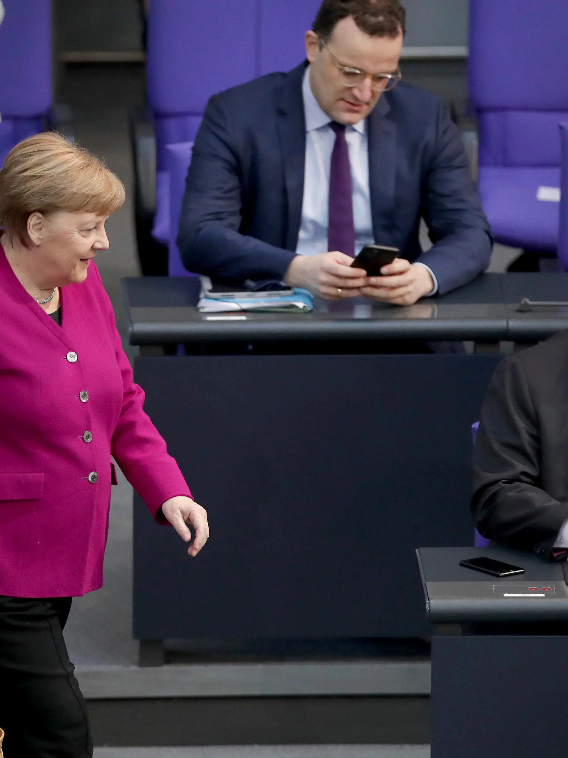 German Chancellor Angela Merkel, left, looks at German Economy Minister Peter Altmaier, right, as she arrives for a meeting of the German federal parliament, Bundestag, at the Reichstag building in Berlin, Germany, Thursday, April 23, 2020. In the center is German Health Minister Jens Spahn. (AP Photo/Michael Sohn)