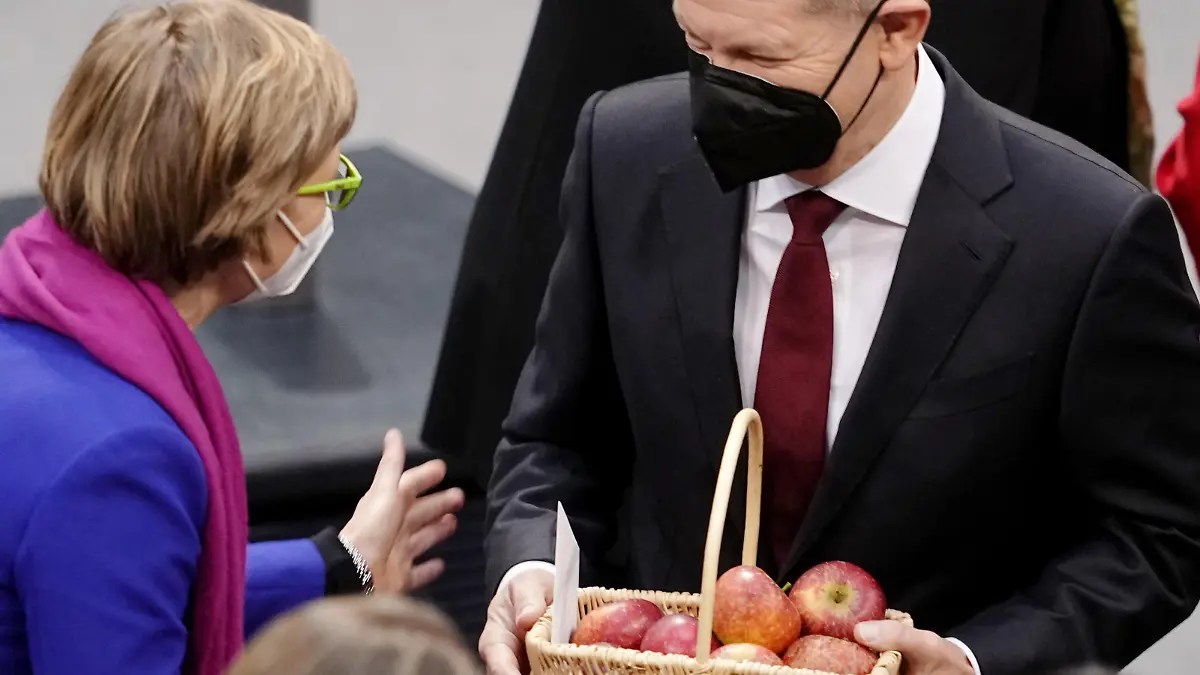 Abgeordnete gratulieren Olaf Scholz (r , SPD) nach seiner Wahl zum Bundeskanzler, der einen Korb Äpfel in der Hand hält. Im Bundestag findet die Wahl und Vereidigung von Scholz zum Bundeskanzler und die Vereidigung der Bundesministerinnen und -minister der neuen rot-grün-gelben Bundesregierung statt. Scholz führt damit die erste Ampelkoalition aus SPD, Grünen und FDP auf Bundesebene an.