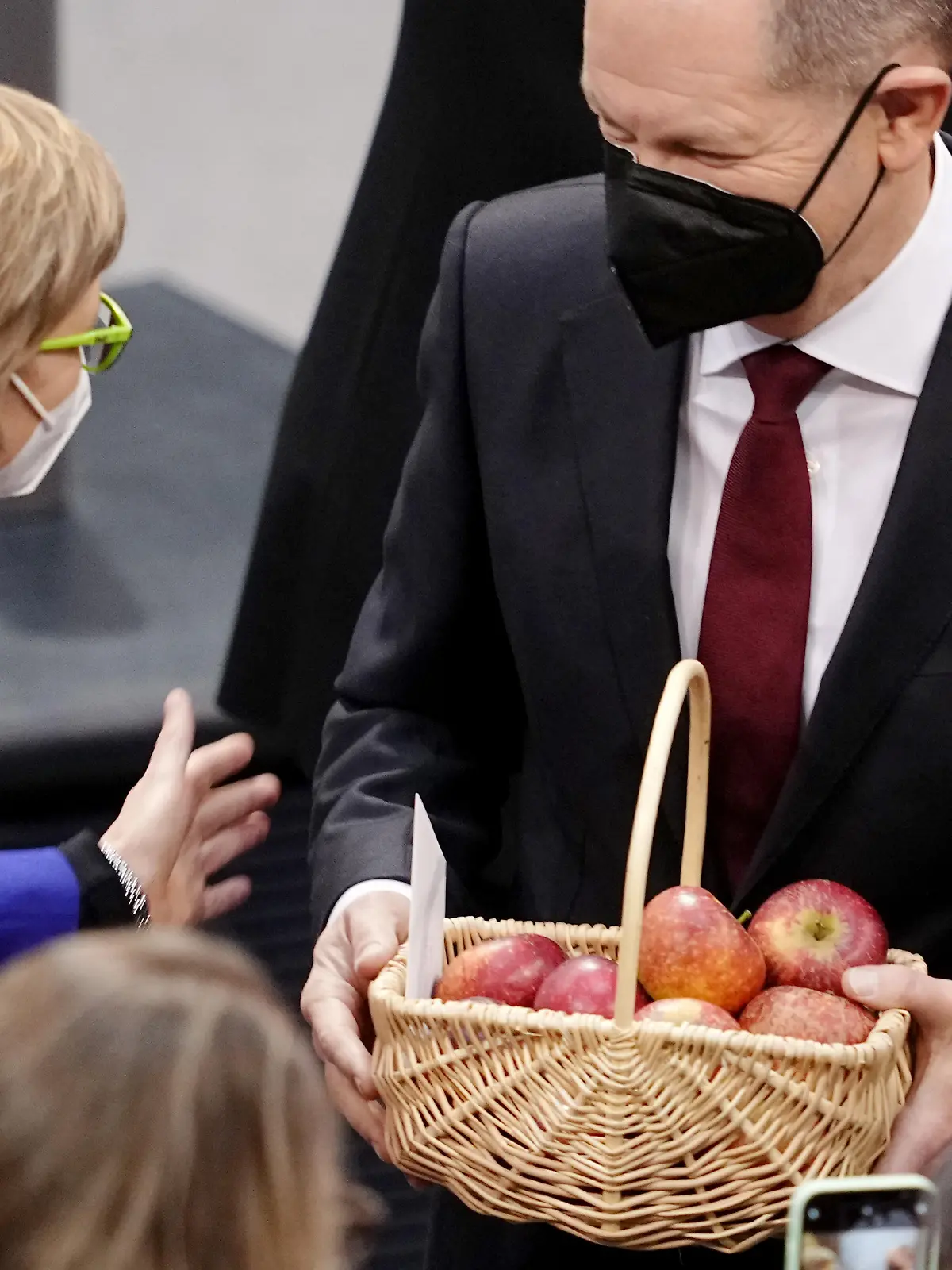 Abgeordnete gratulieren Olaf Scholz (r , SPD) nach seiner Wahl zum Bundeskanzler, der einen Korb Äpfel in der Hand hält. Im Bundestag findet die Wahl und Vereidigung von Scholz zum Bundeskanzler und die Vereidigung der Bundesministerinnen und -minister der neuen rot-grün-gelben Bundesregierung statt. Scholz führt damit die erste Ampelkoalition aus SPD, Grünen und FDP auf Bundesebene an.