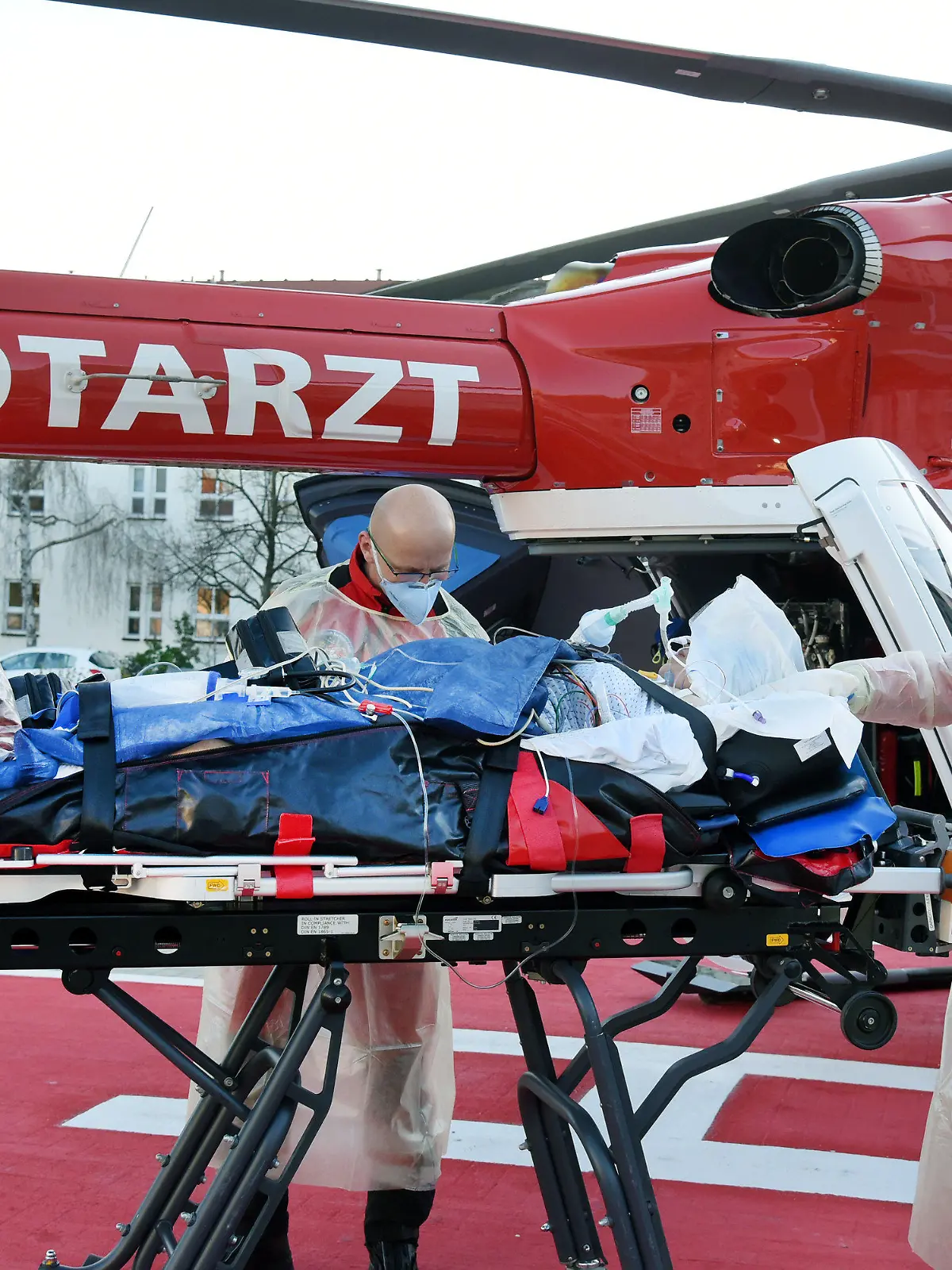 02.12.2021, Sachsen-Anhalt, Wittenberg Lutherstadt: Von der Corona-Intensivstation vom Evangelischen Krankenhaus Paul Gerhard Stift wird eine an Covid 19 erkrankte Schwangere von dem Notarzt der Luftrettung Alexander Kampe (r) und Notfallsanitäter Mario Gustke zum Hubschrauber der DRF gebracht. Die Frau wird aus medizinischen Gründen in das Pränatalzentrum der Universitätsklinik Halle verlegt. Das Krankenhaus in Wittenberg hat seine sonst 10 Intensivplätze auf 16 aufgestockt, die gegenwärtig auch alle belegt sind. Foto: Waltraud Grubitzsch/dpa-Zentralbild +++ dpa-Bildfunk +++