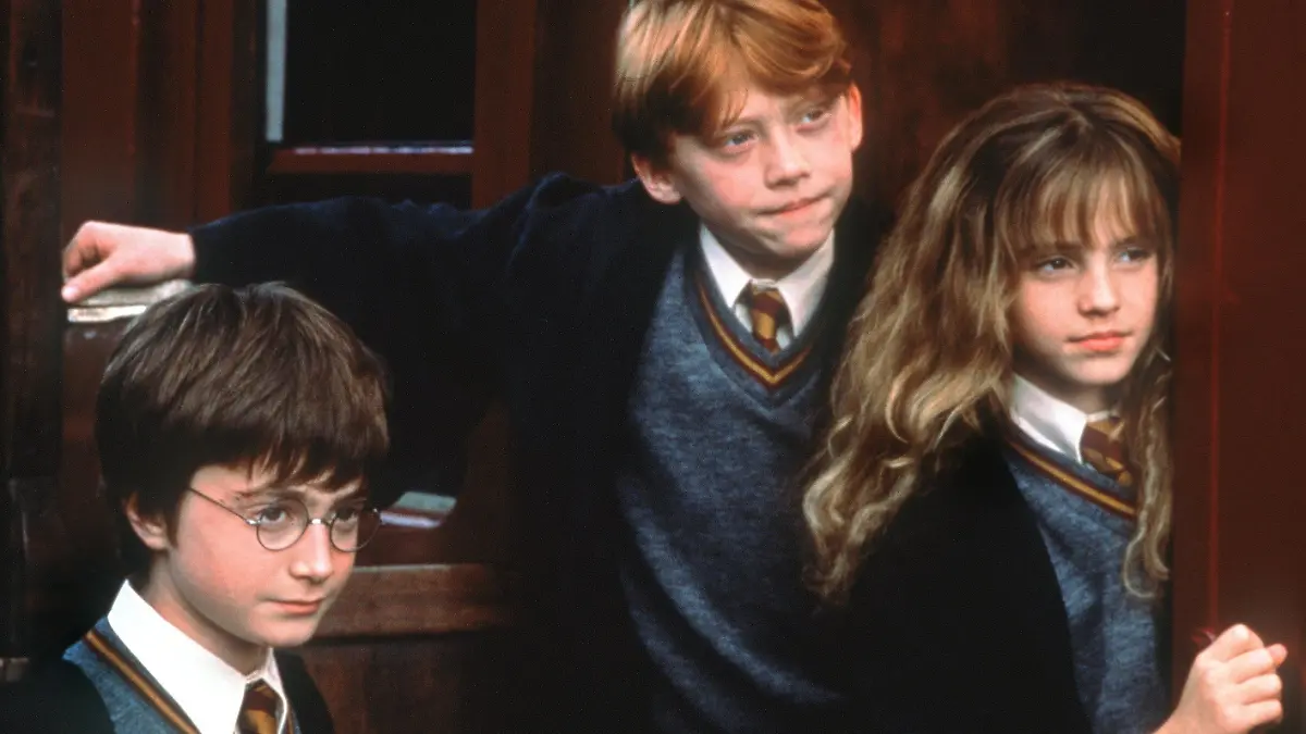 ARCHIV - Voller Erwartung stehen die Zauberlehrlinge Harry Potter (Daniel Radcliffe, l.), Ron Weasley (Rupert Grint) und Hermine Granger (Emma Watson) im Kinofilm "Harry Potter und der Stein der Weisen" an der Tür zur Hogwarts-Schule für Zauberkunst (Szenenfoto, Illustration zum Thema Schuluniform). Harry Potter trägt die wohl bekannteste britische Schuluniform - nicht nur im Vereinigten Königreich würden Kinder gern das Wappen der Hogwart-Zaubererschule zur Schau stellen. Auch in vielen Ländern ohne Schuluniformpflicht dürften "Harry Potter"-Filme dazu beigetragen haben, den Gedanken an eine Identität fördernde Gemeinschaftskleidung für Kinder als "Botschafter" ihrer Schule zu fördern. Foto: Warner (zu dpa-Korr. "Das Supermodel für Schuluniformen ist ein Brite: Harry Potter" vom 10.05.2006) +++(c) dpa - Bildfunk+++
