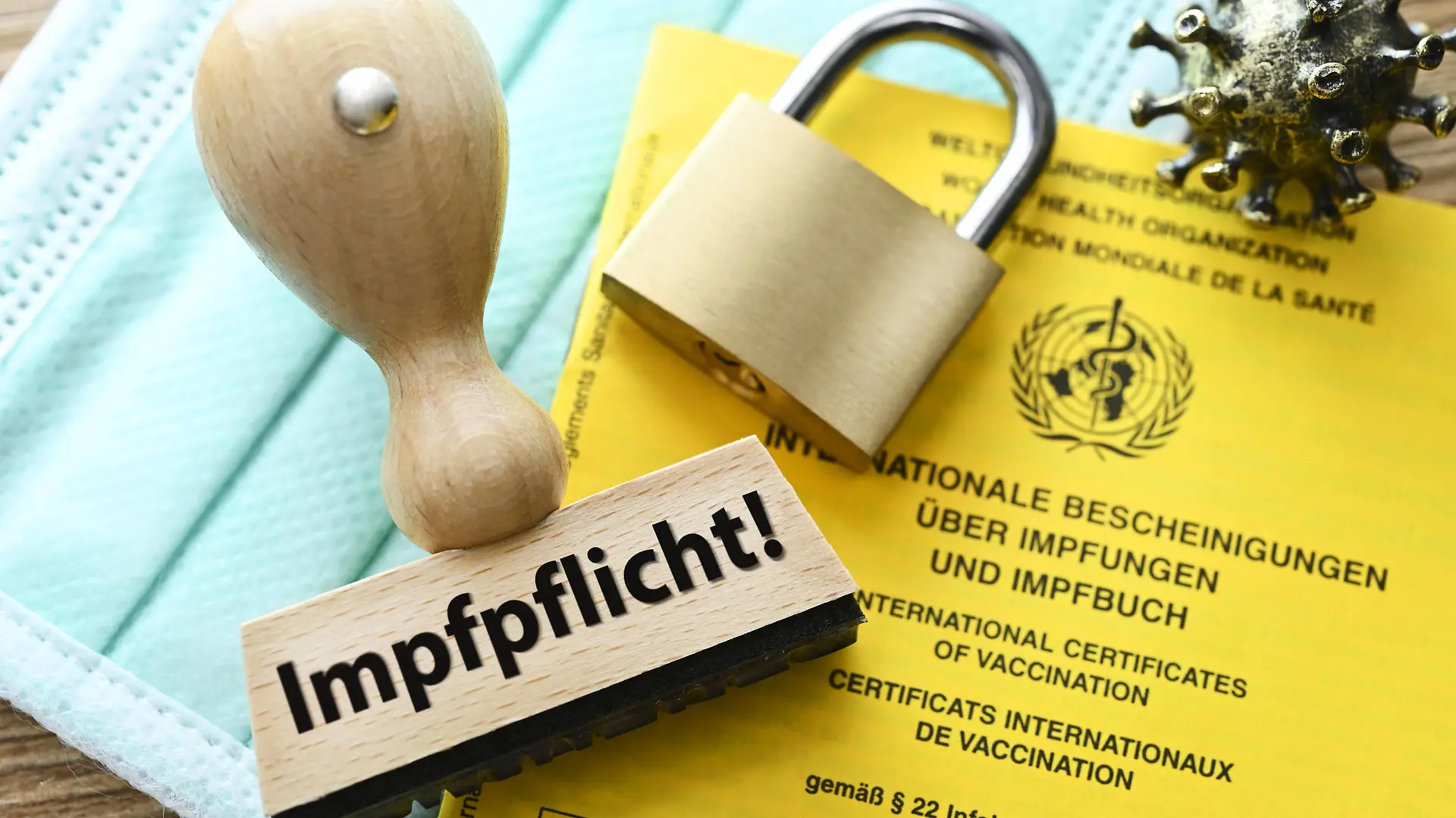 FOTOMONTAGE, Stempel mit der Aufschrift Impfpflicht auf einem Impfausweis und Vorhängeschloss *** PHOTOMONTAGE, stamp with the inscription compulsory vaccination on a vaccination card and padlock