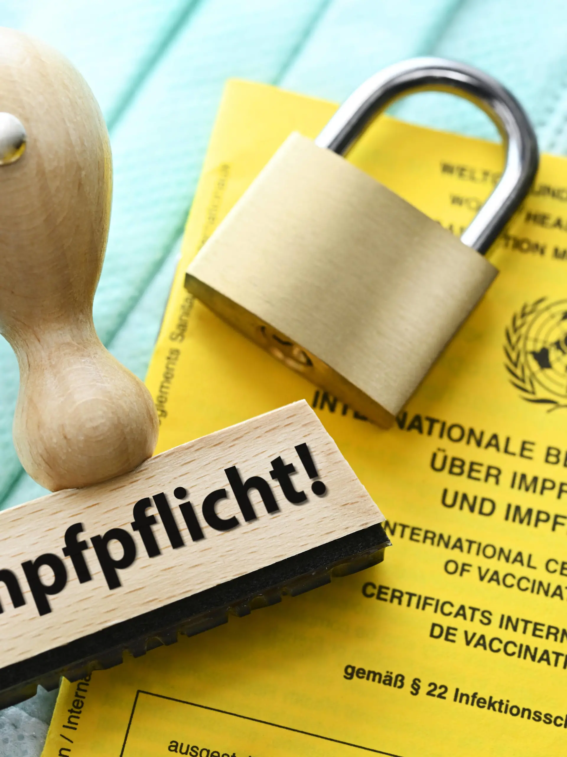  FOTOMONTAGE, Stempel mit der Aufschrift Impfpflicht auf einem Impfausweis und Vorhängeschloss *** PHOTOMONTAGE, stamp with the inscription compulsory vaccination on a vaccination card and padlock