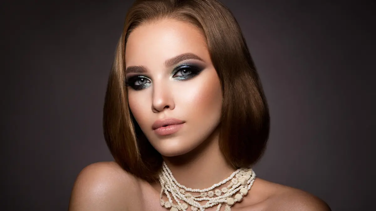 Glamour portrait of beautiful girl model with makeup and romantic hairstyle. Fashion shiny highlighter on skin, sexy gloss lips make-up and dark eyebrows.