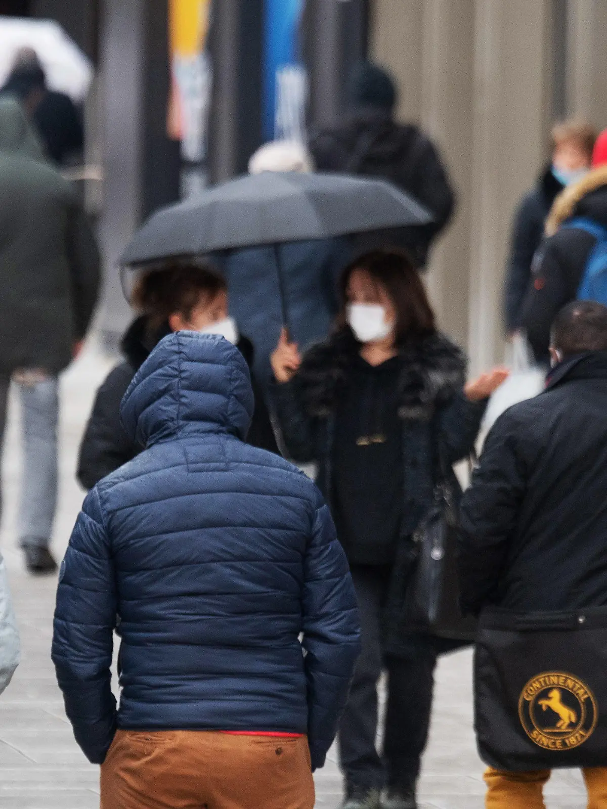 02.12.2021, Hessen, Frankfurt/Main: Passanten gehen bei Regenwetter über die Zeil in Frankfurt am Main. Angesichts der angespannten Lage verschärft Hessen erneut die Corona-Regeln. Von neuen Kontaktbeschränkungen, die ab kommenden Sonntag gelten sollen, sind dann speziell Ungeimpfte betroffen. Foto: Boris Roessler/dpa +++ dpa-Bildfunk +++
