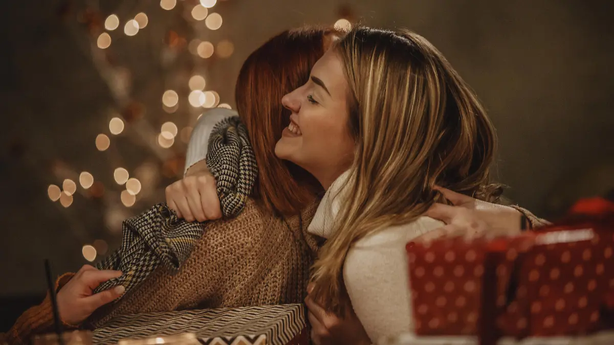 Young woman and her mother are hugging during opening Christmas presents.