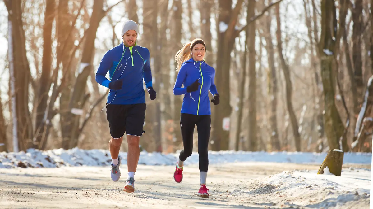 Young couple in the winter running together in nature